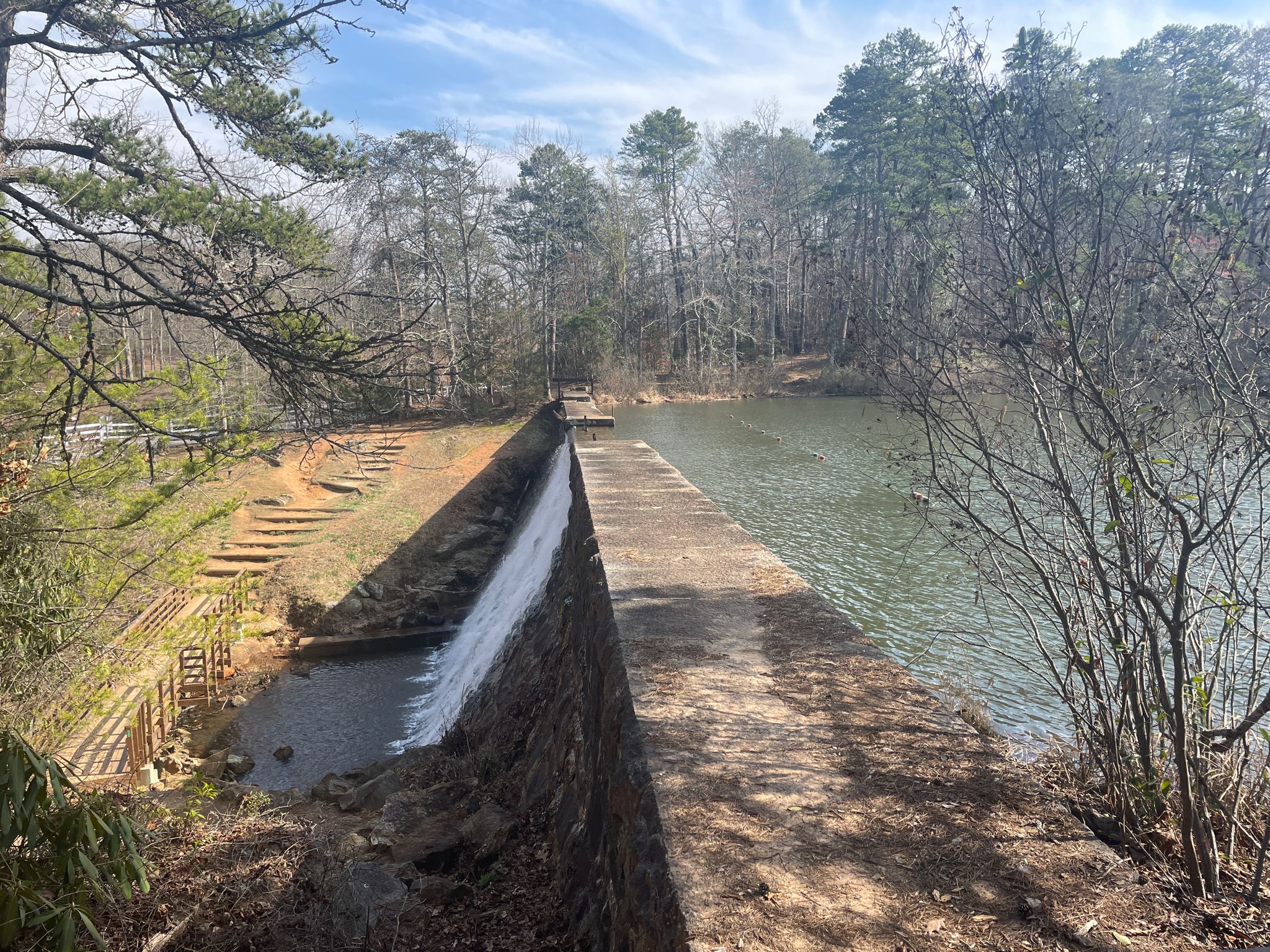 A long concrete dam with water flowing, beside a lake and forest. - Lake Placid Dam – Swamp Rabbit Trail loop from Rutherford Road @ Dollar General