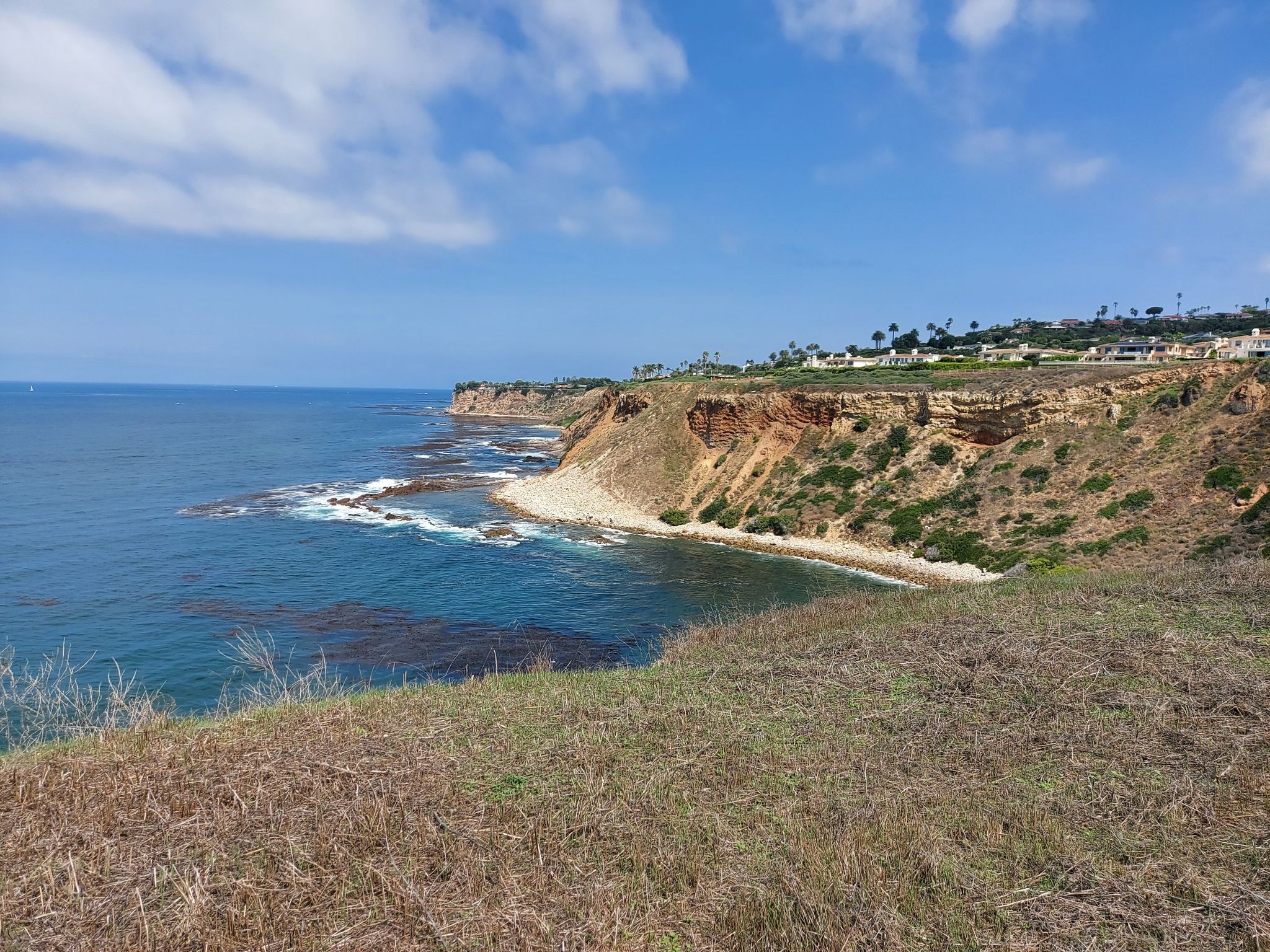 Ocean coastline with rugged cliffs and a small beach under a partly cloudy sky. - Point Vicente Lighthouse loop from Palos Verdes Estates