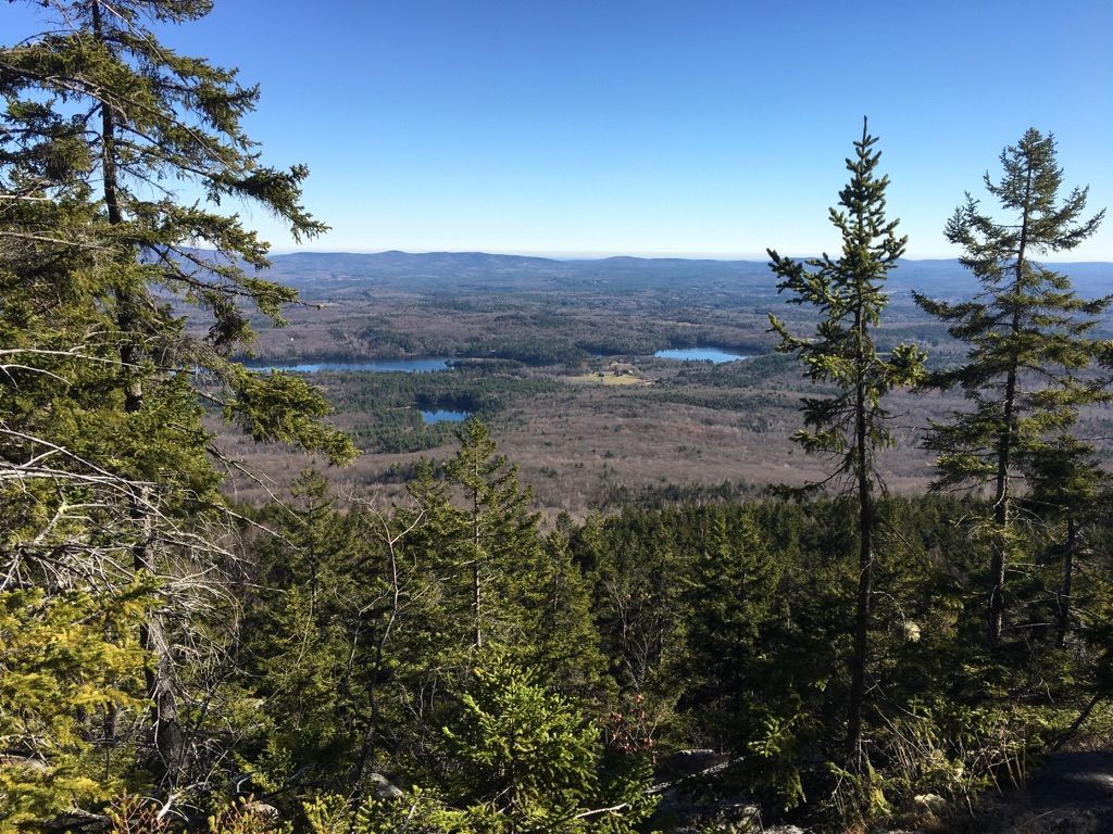 Forested mountain view with two lakes in the distance under a clear blue sky. - Cascade Link Trail