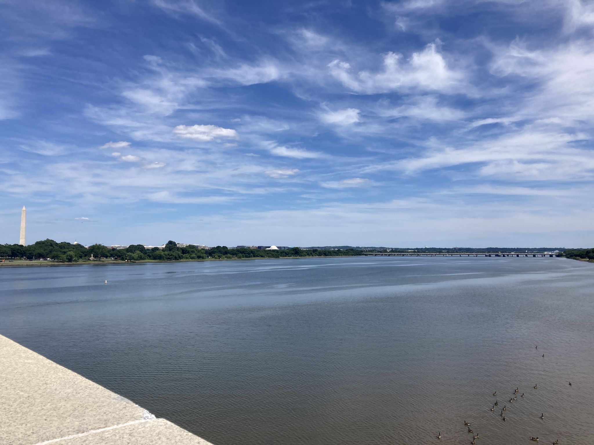 A wide river stretches to the horizon with a distant monument under a cloudy sky. - Washington Monument – Korean War Veterans Memorial loop from Potomac Avenue