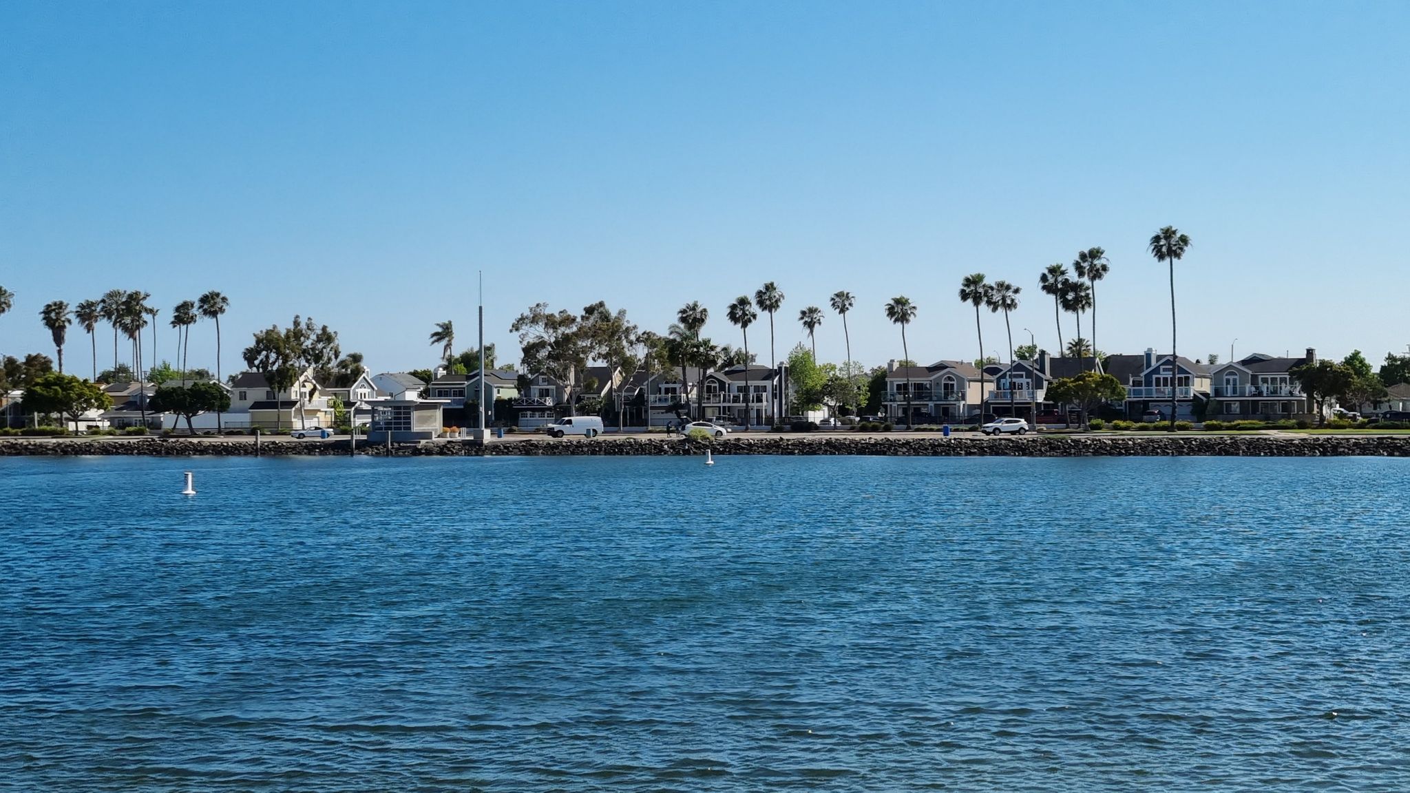 Waterfront houses and palm trees line a calm blue waterway on a sunny day. - Marine Stadium and Marina Pacifica Loop