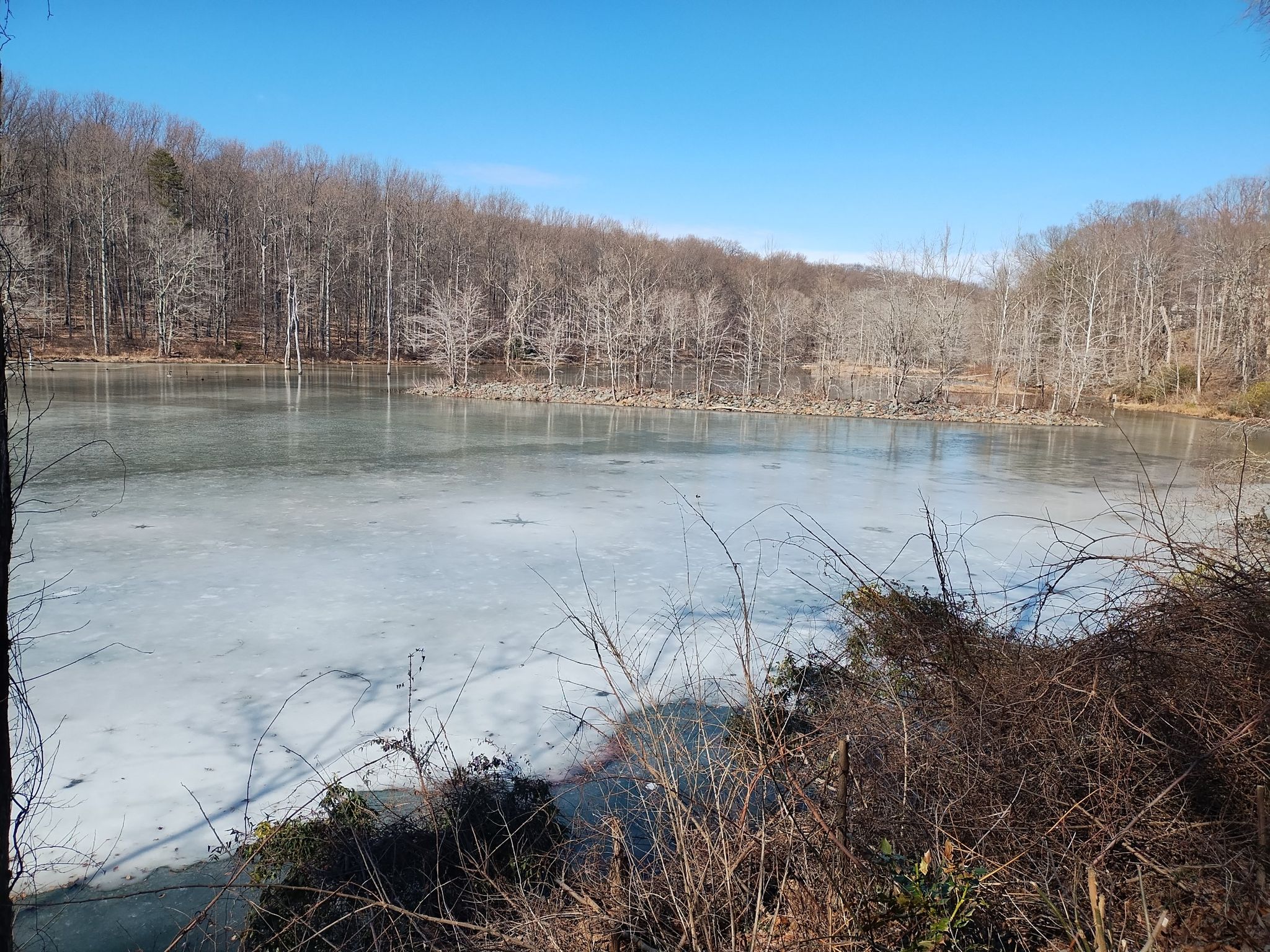 Partially frozen lake surrounded by bare trees under a clear blue sky. - Little Seneca Lake – Little Seneca Lake loop from Boyds