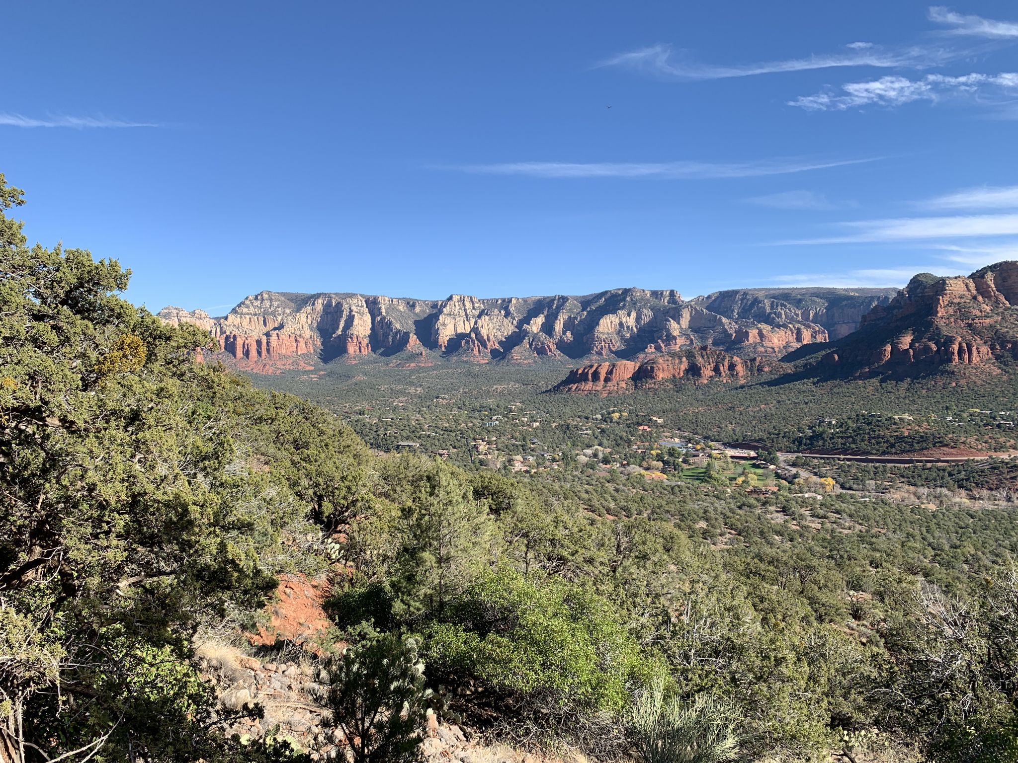 Expansive view of distant red rock mountains and a green valley under clear sky. - Airport Loop Trail