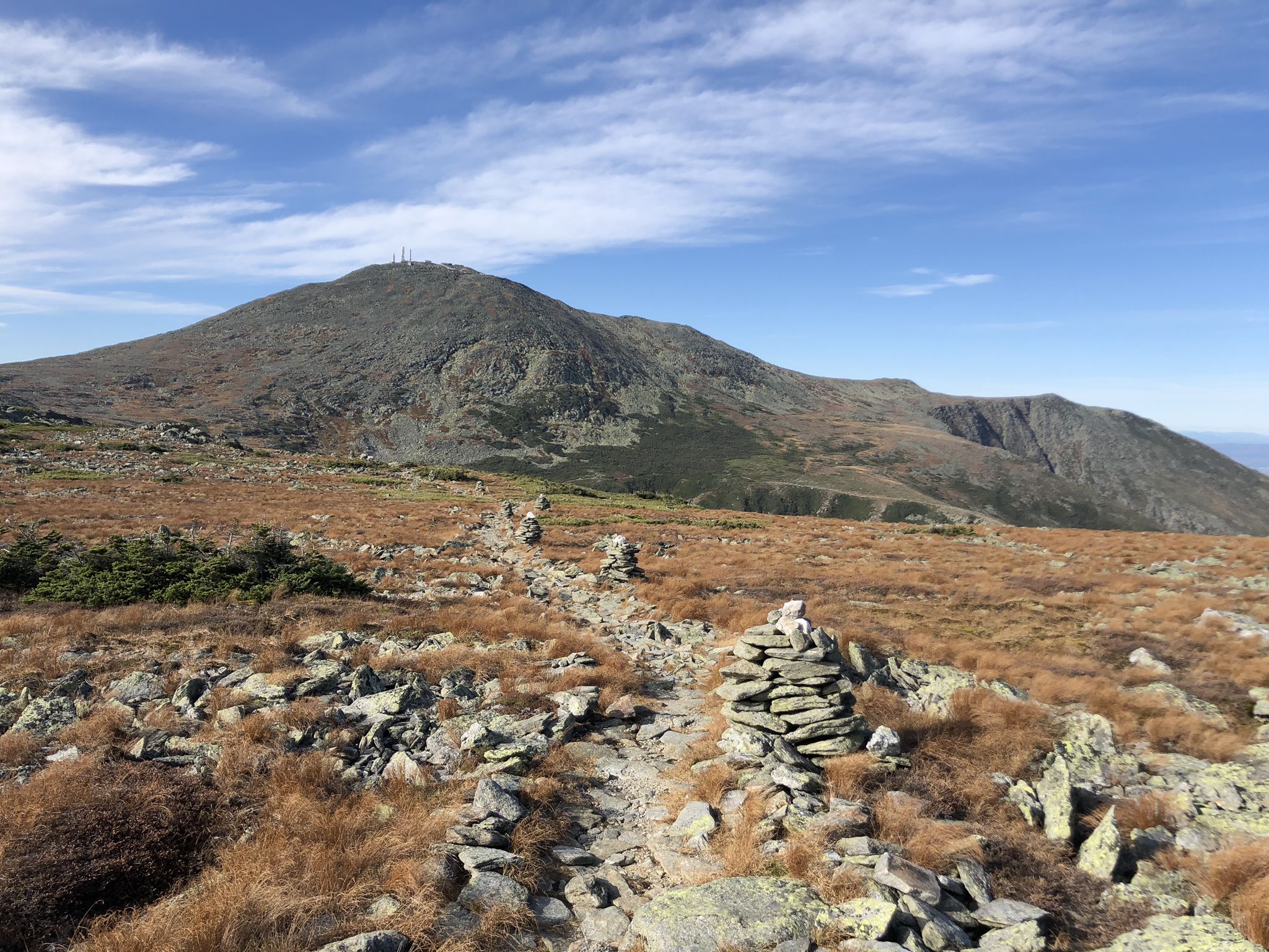Rocky mountain path with cairns, dry grass, and a distant peak under blue sky. - Mount Washington via Huntington Ravine and Boott Spur Trail