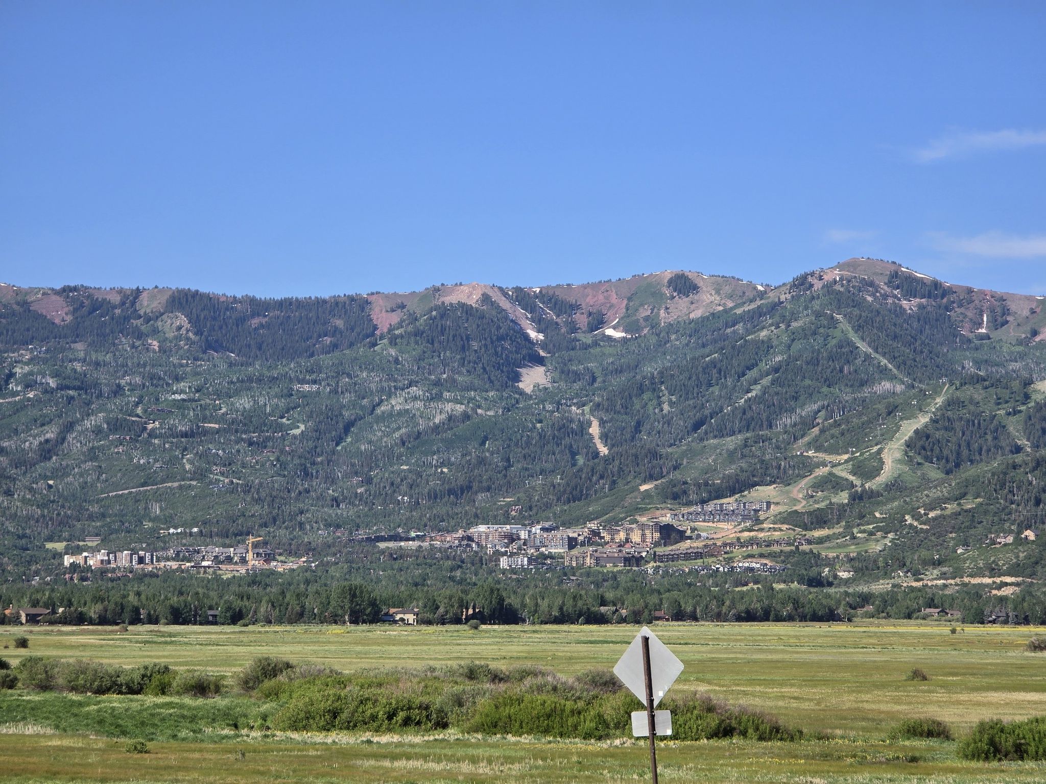Green mountains with buildings at their base, overlooking a grassy field. - Union Pacific Rail Trail and Echo Reservoir Loop