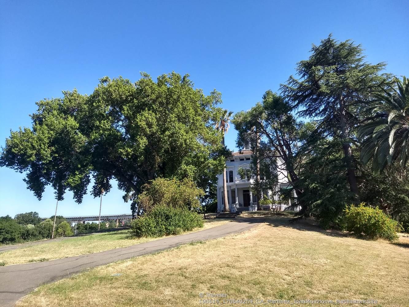 A large white house nestled among green trees on a sunny day. - Mount Helen & Mount Wanda loop