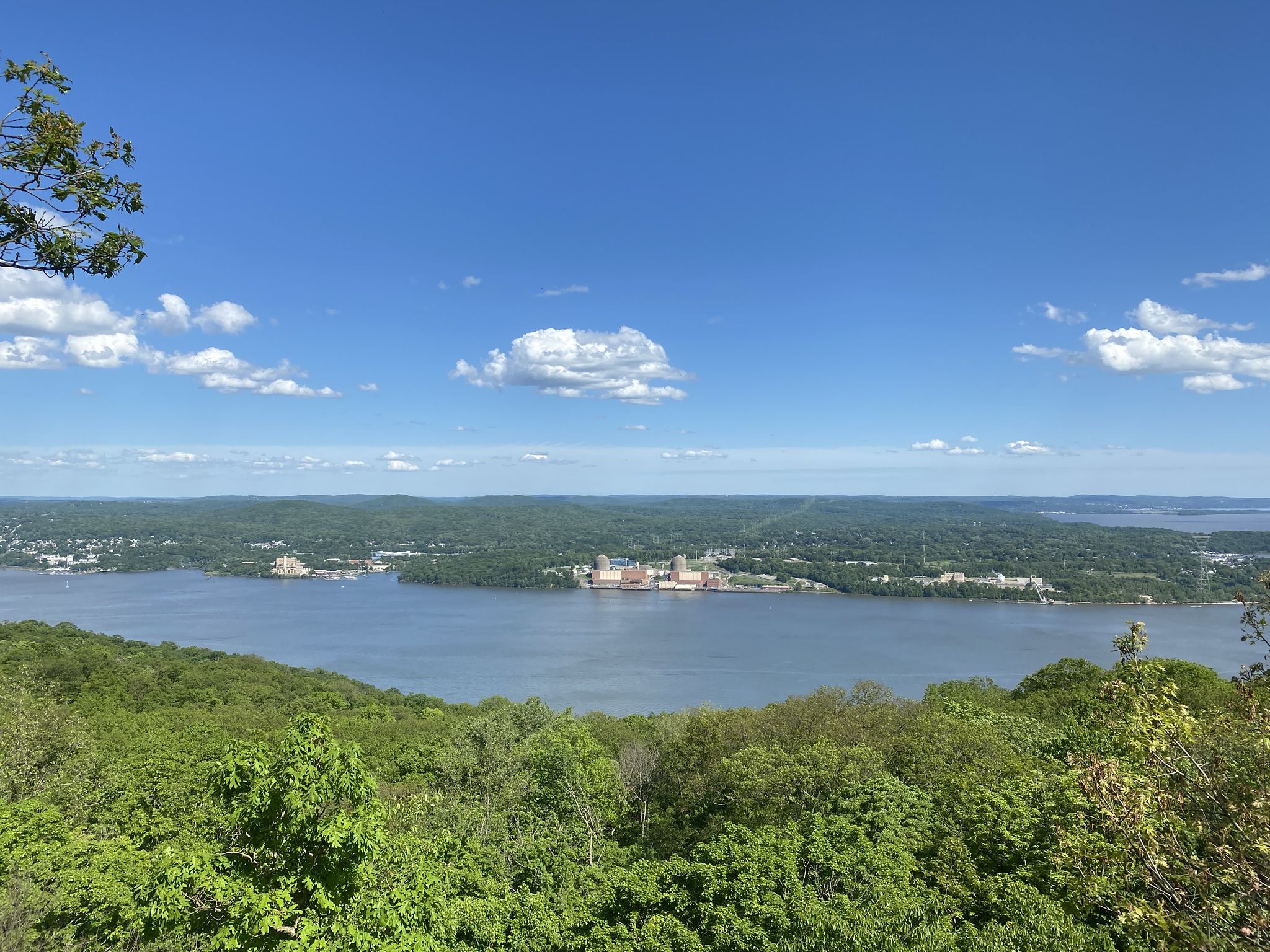 Panoramic view of a wide river, distant buildings, and green hills under blue sky. - Ramapo-Dunderberg and Timp-Torne Trail Loop