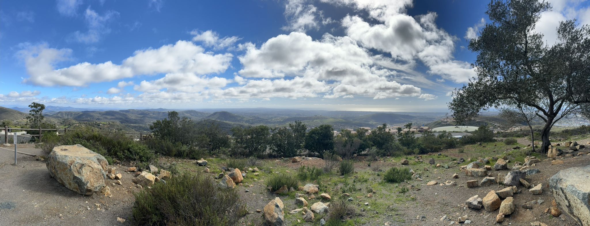 Panoramic view of rolling hills, distant ocean, and a partly cloudy sky. - Double Peak Summit View – Double Peak loop from Ridgeline Trailhead