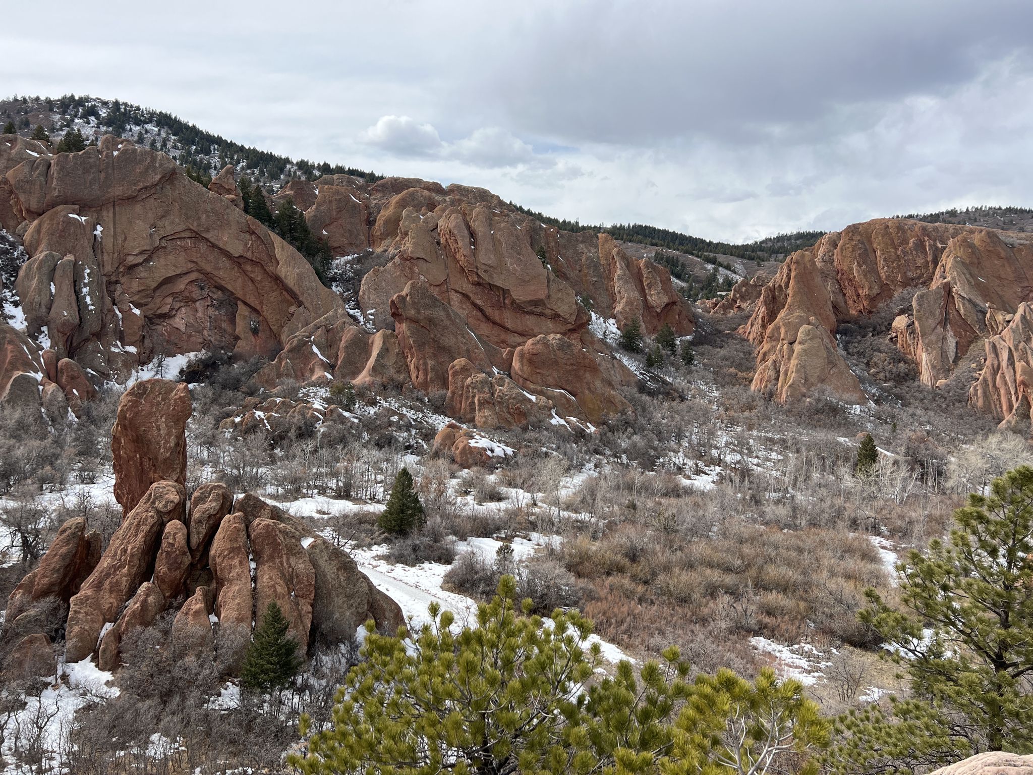 Red rock formations with snow on the ground under a cloudy sky. - Fountain Valley Loop