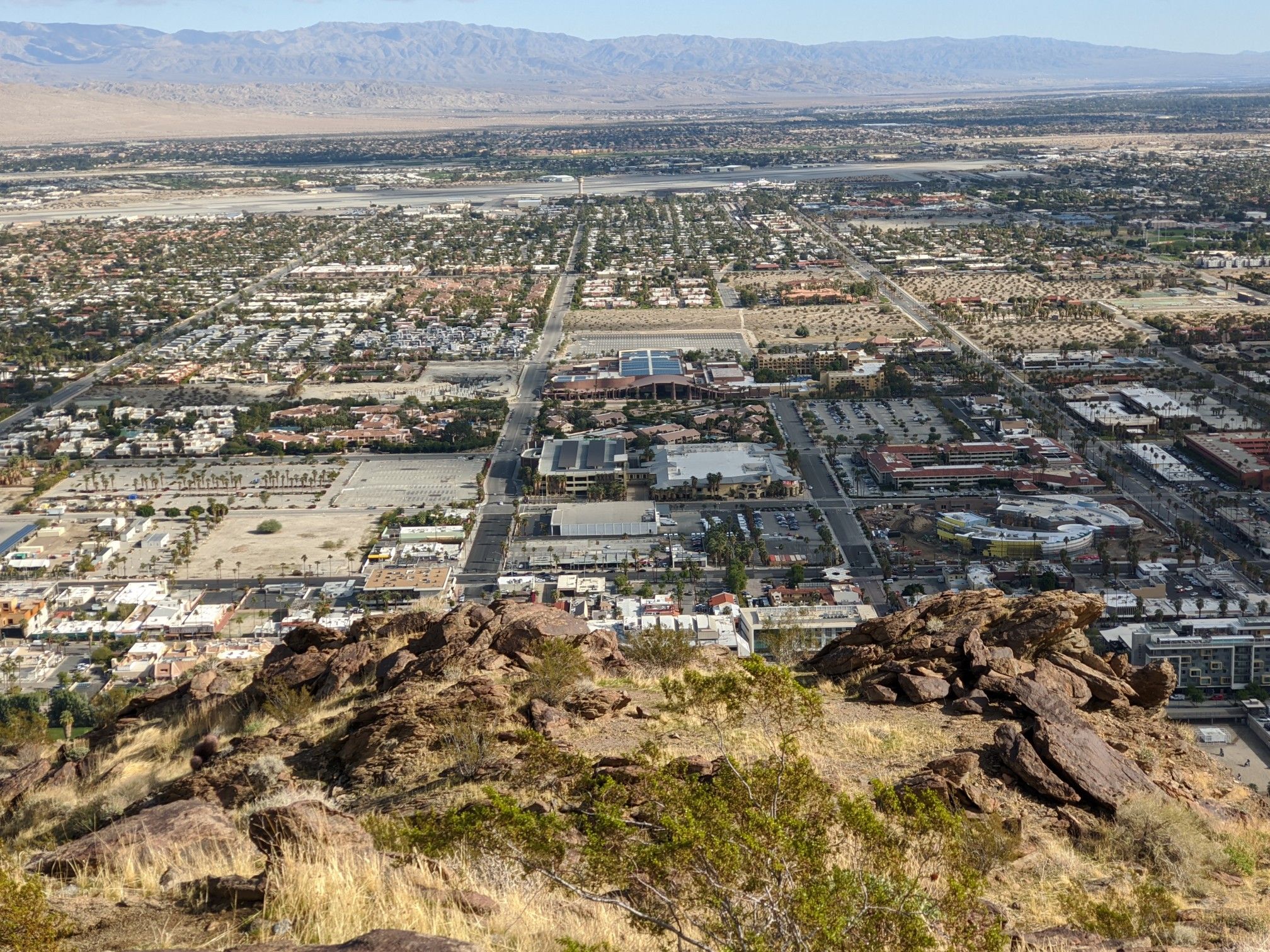 Overhead view of a sprawling city from a rocky, arid mountain slope. - Museum Trail