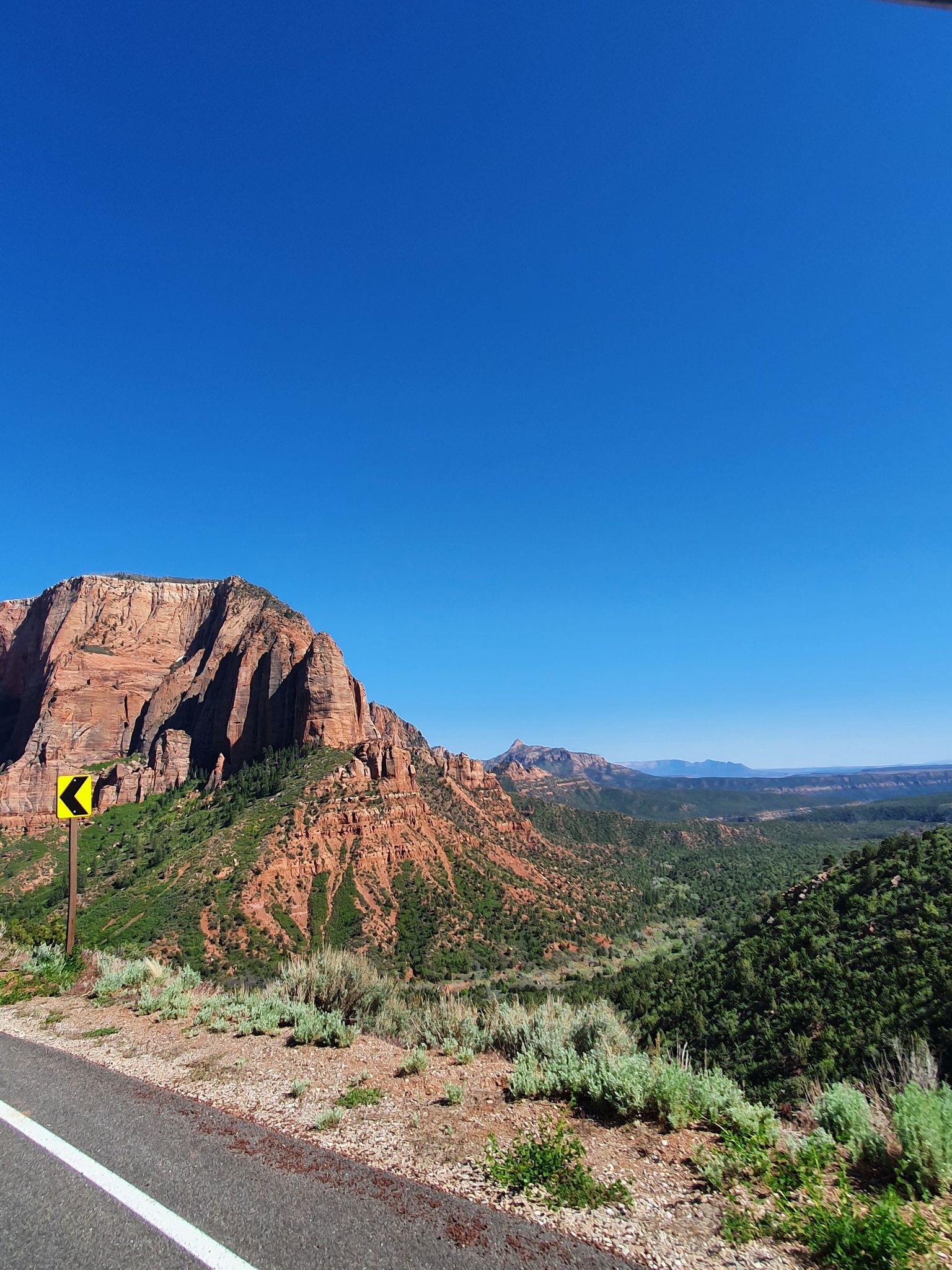 Roadside view of red rock mountains and green valleys under a clear blue sky. - Timber Creek Overlook Trailhead and Kolob View Point via Kolob Canyon Road