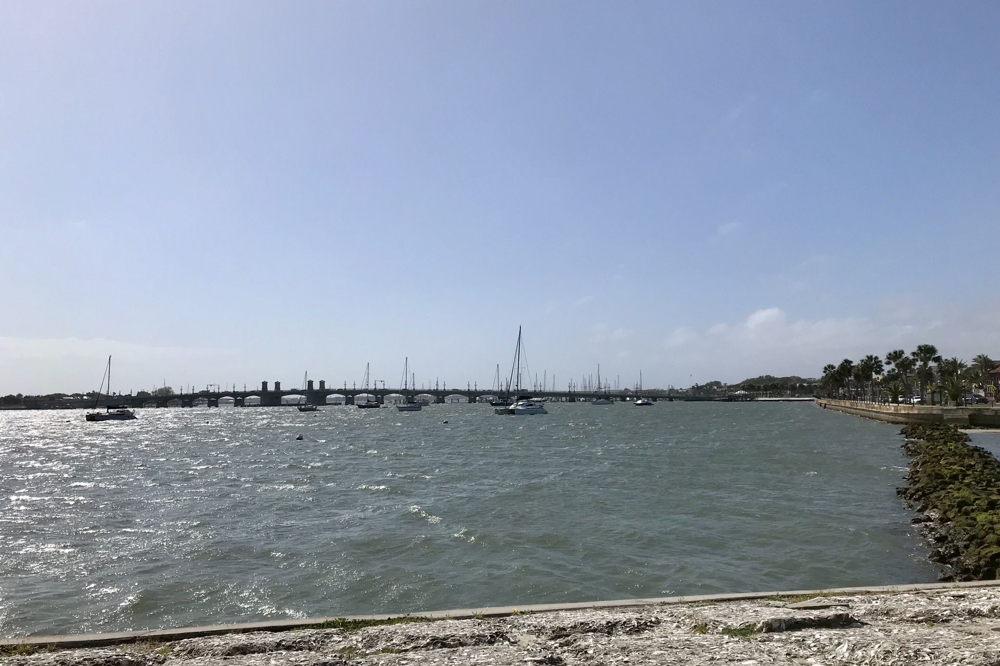 Choppy water with many boats and a distant bridge under bright sky. - East Coast Greenway Trail