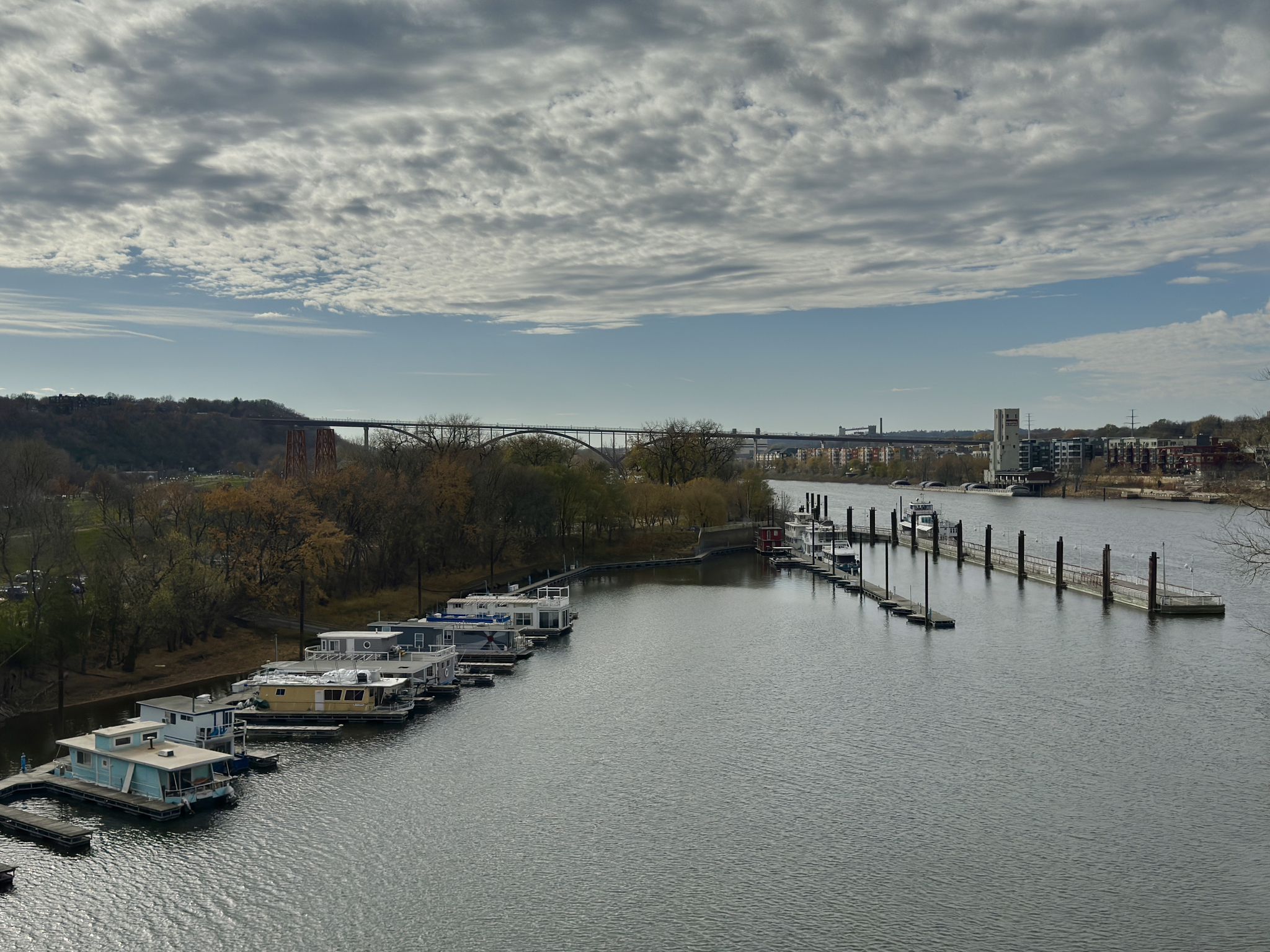 River with docked boats, a distant bridge, and cloudy sky. - St. Paul to White Bear Lake loop