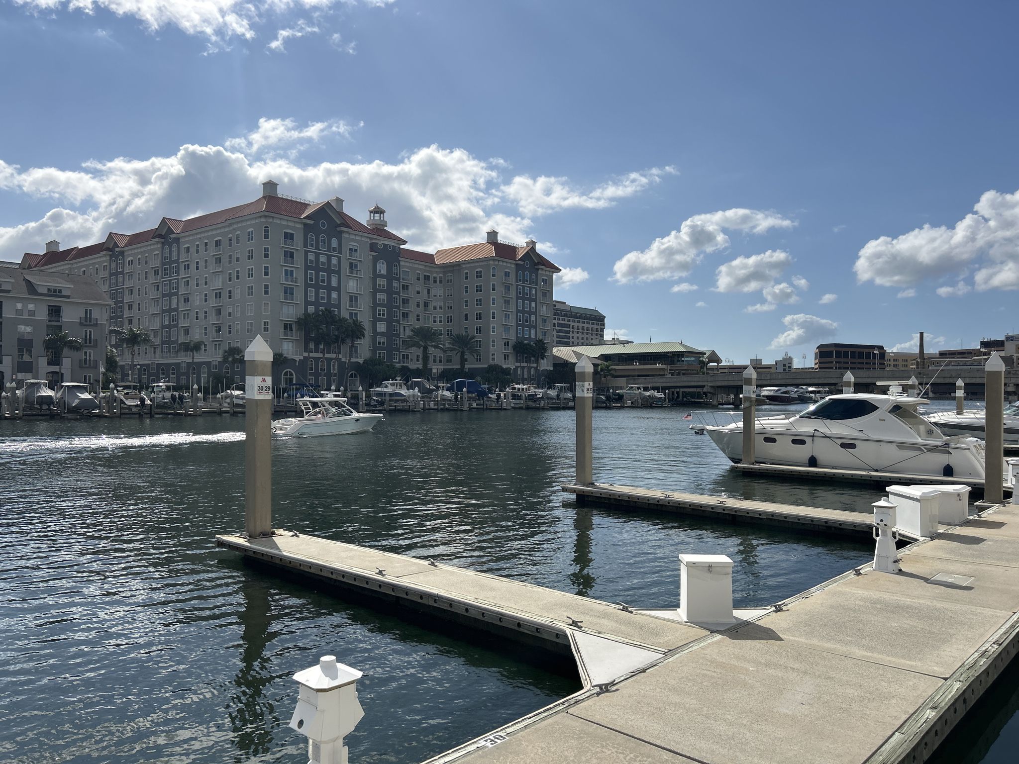 Marina with boats and a large building under a bright, cloudy sky. - Tampa Cruise Port – Selmon Greenway loop from Hyde Park