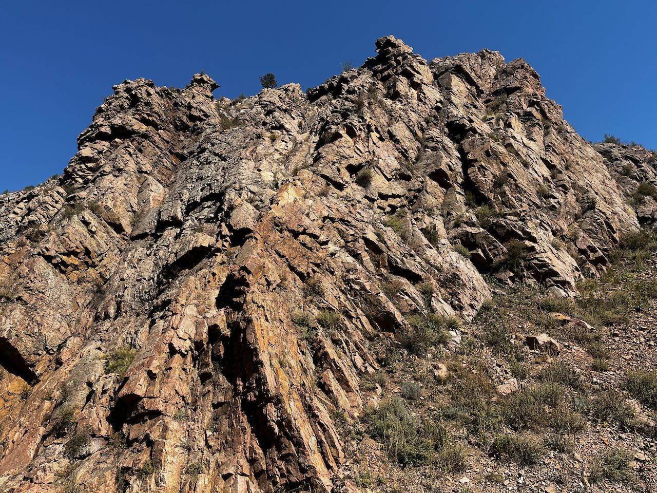 Steep, rugged rocky cliff face under a clear blue sky. - Tucker Gulch – Golden City Brewery (GCB) loop from Applewood