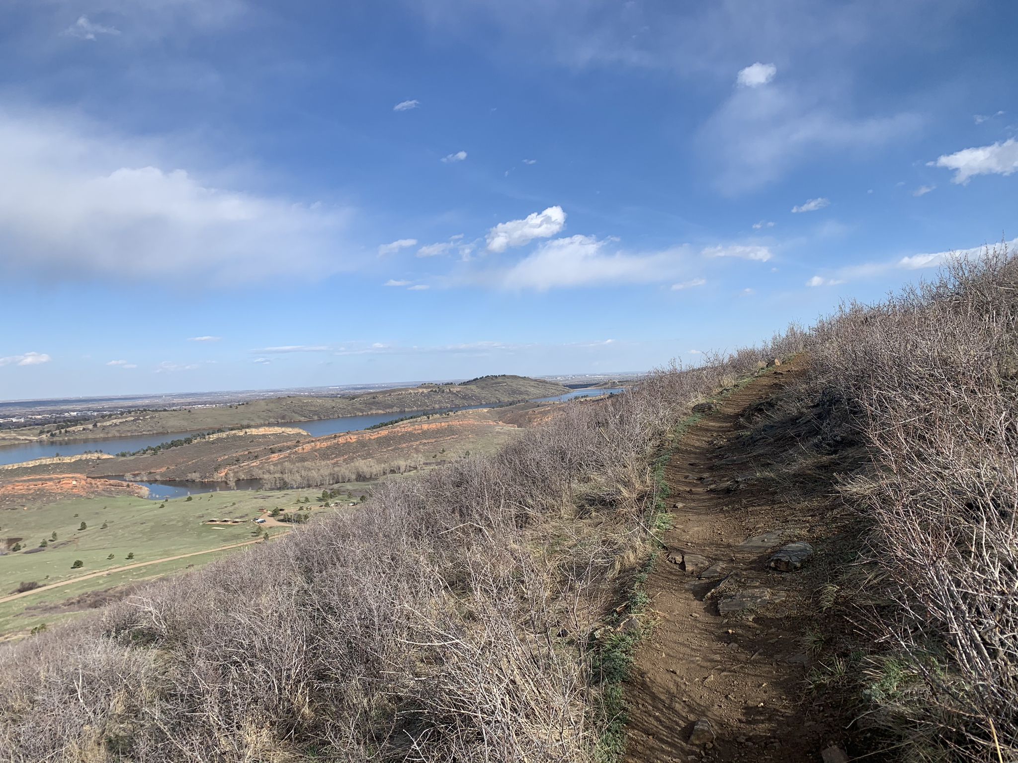 Dirt trail on a hillside overlooking lakes and plains under a partly cloudy sky. - Timber, Kimmons, and West Valley Trail Loop