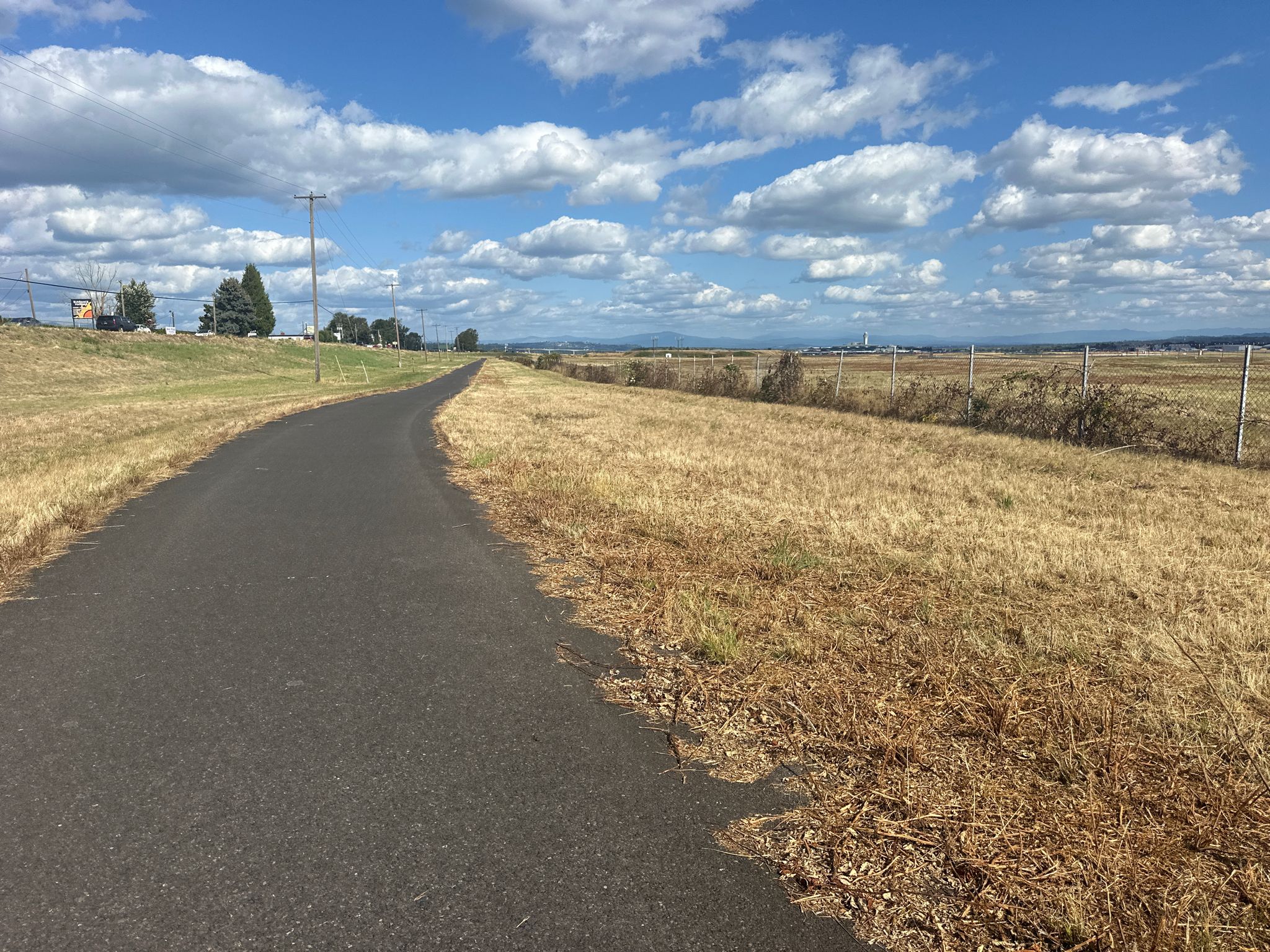 Paved path curves through a dry, golden field under a cloudy blue sky. - Willamette and Columbia Rivers loop via the 40 Mile Loop trail