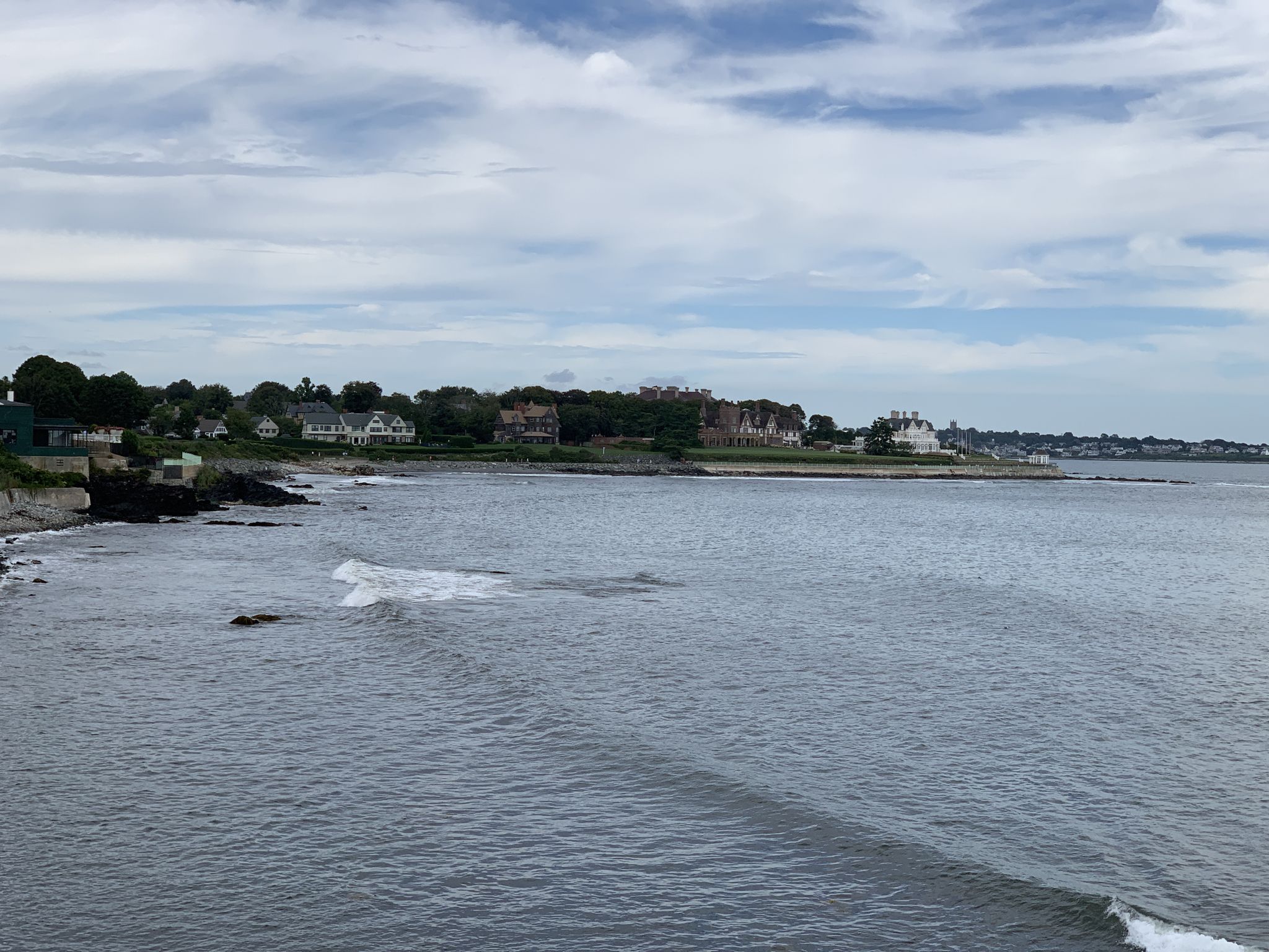 Wide view of ocean waves approaching a distant shoreline with houses. - Vinland Estate (McAuley Hall) – Astor's Beechwood Mansion loop from Newport