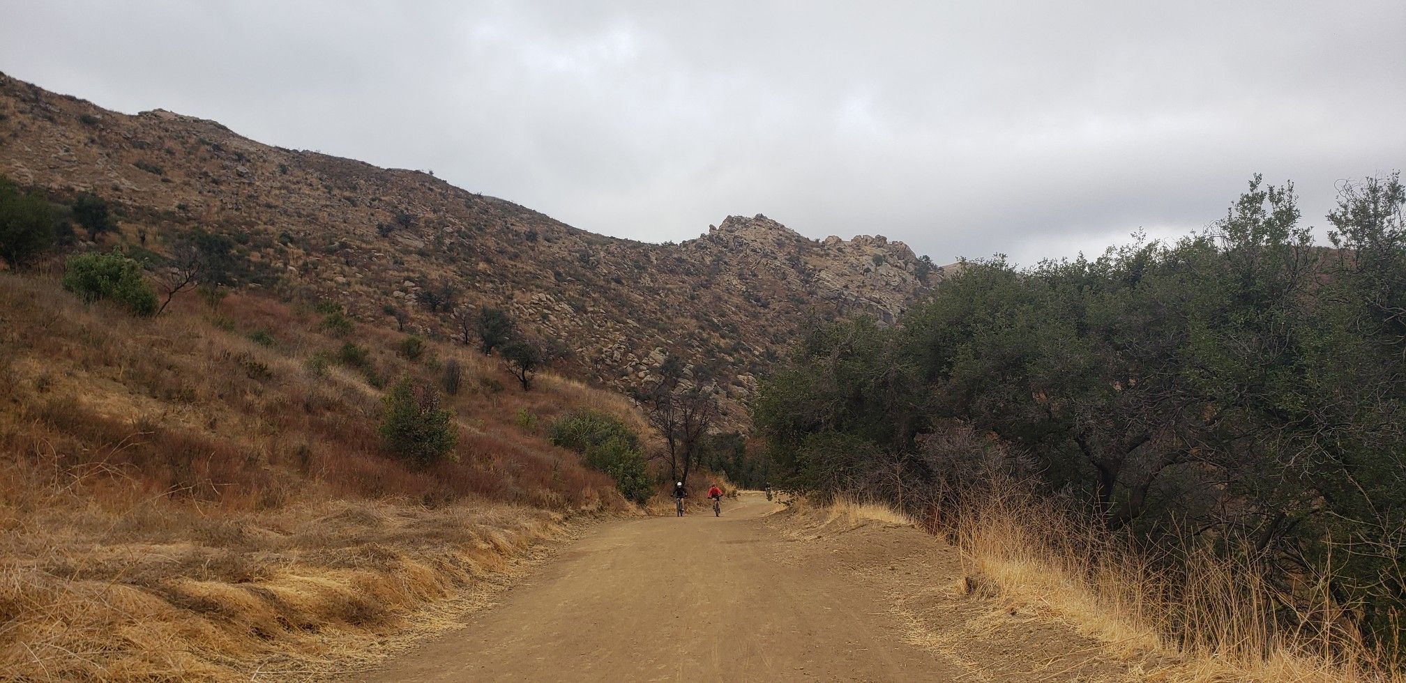 Dirt road with two distant figures, flanked by hills and trees. - Lang Ranch Ridge, Meadow Vista and Albertson Loop