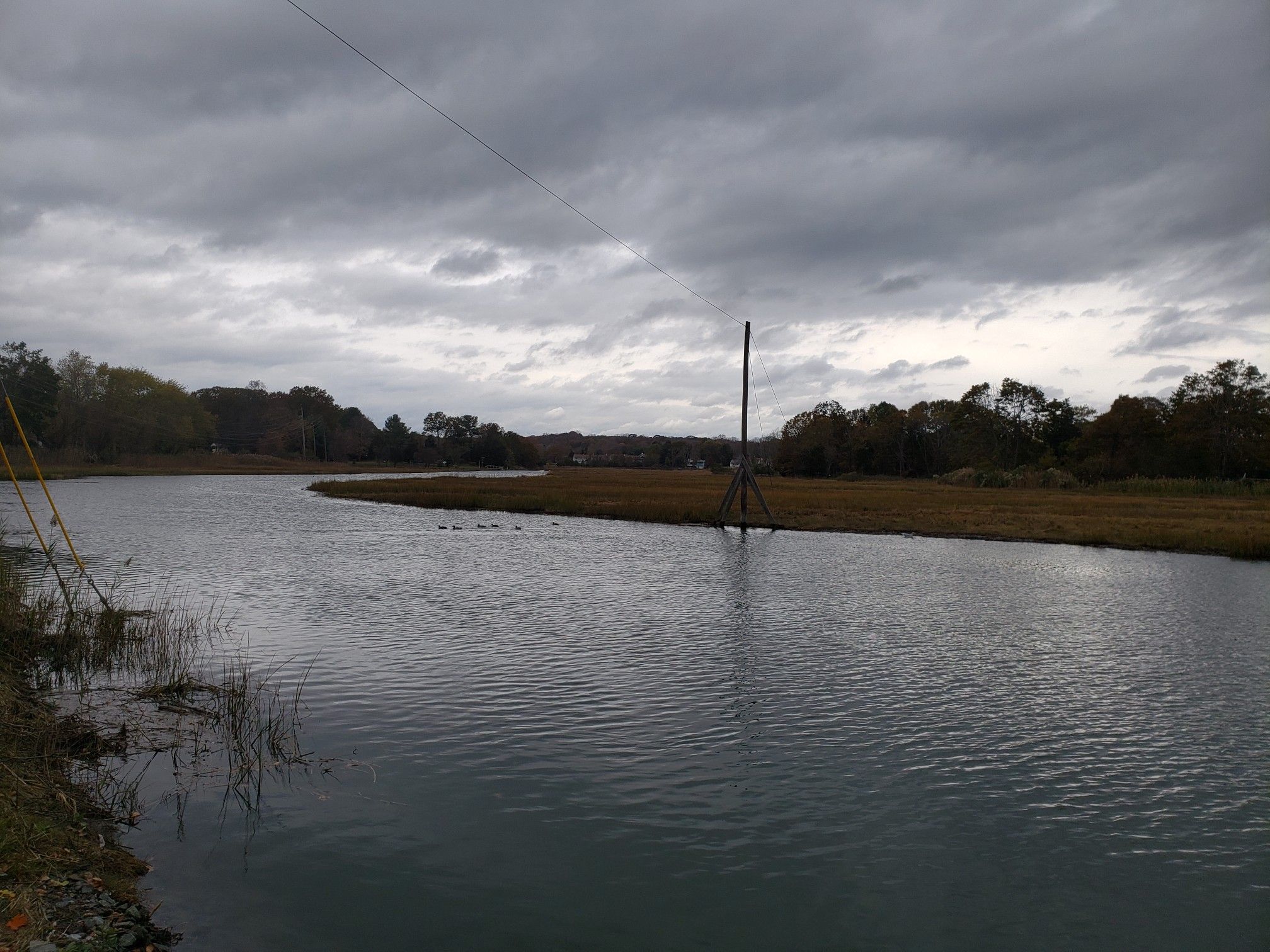 A wide river with marshy banks under a dark, cloudy sky. - Hotchkiss Cove Beach – Guilford Historic Town Center loop from East Haven