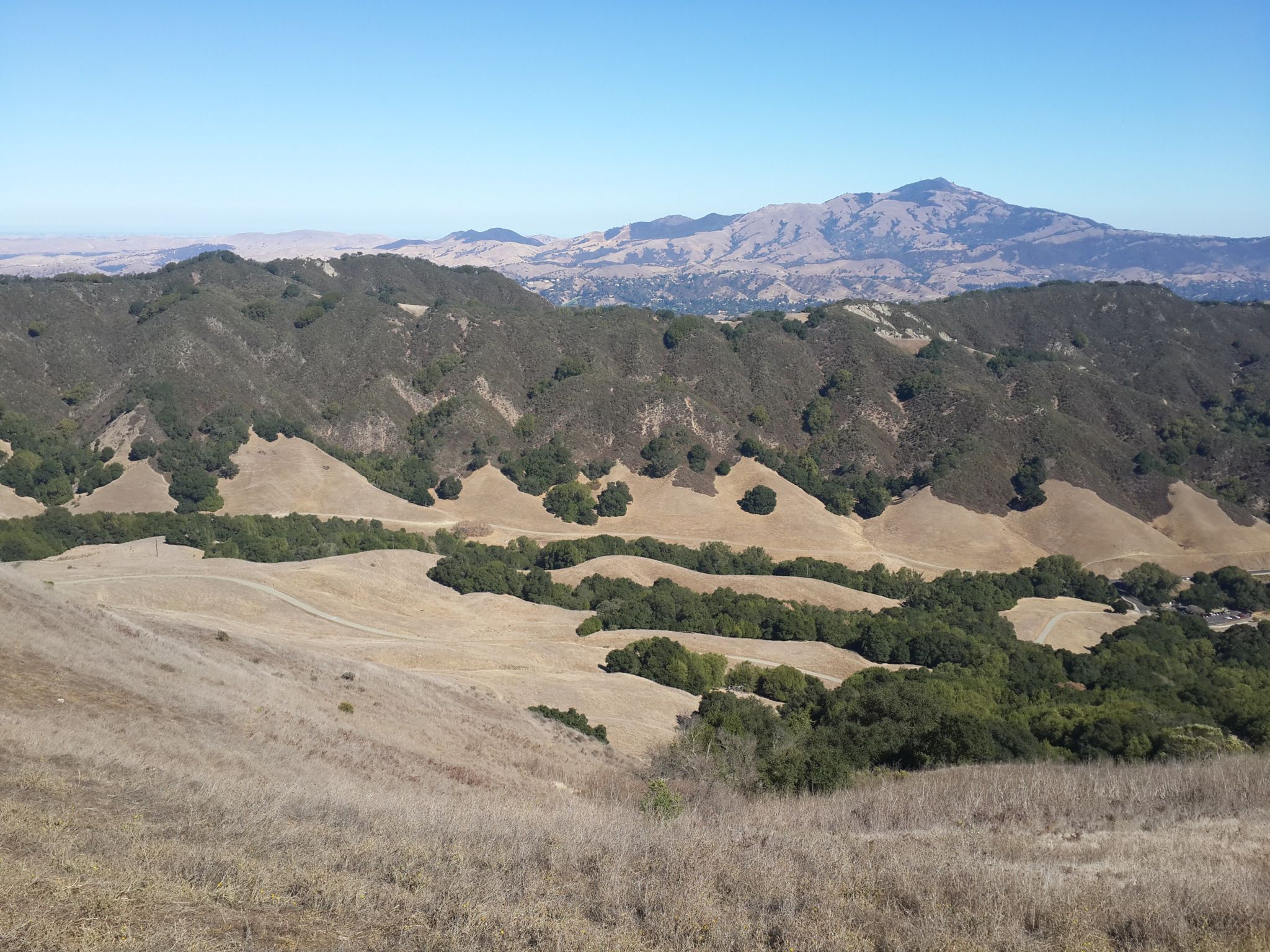 Expansive view of dry hills, green valleys, and distant mountains under a clear sky. - Carr Ranch Loop and Rocky Ridge Trail