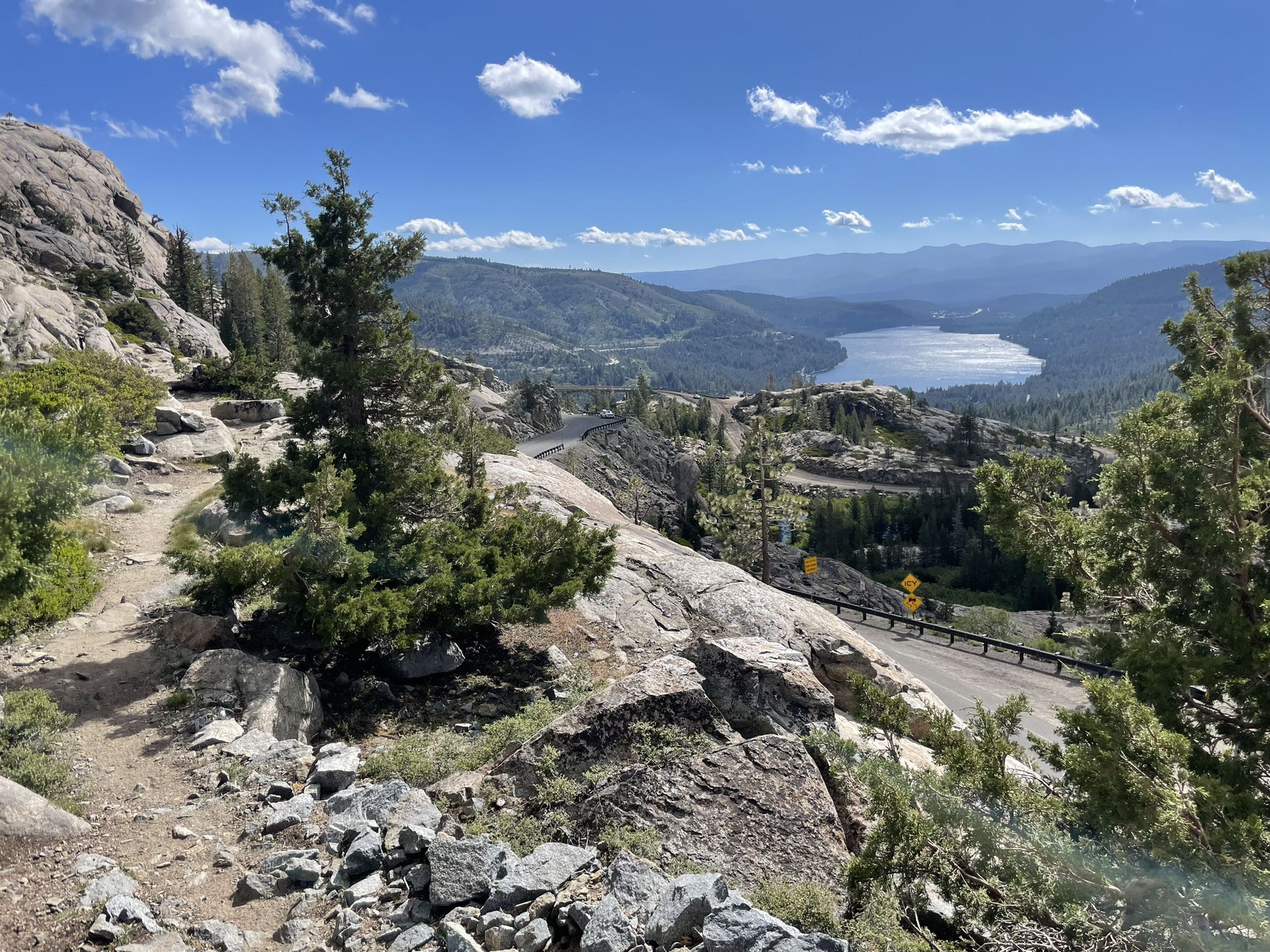 Rocky mountain path overlooking a winding road, lake, and distant mountains. - Pacific Crest Trail: CA Section L - Donner Summit to Highway 49