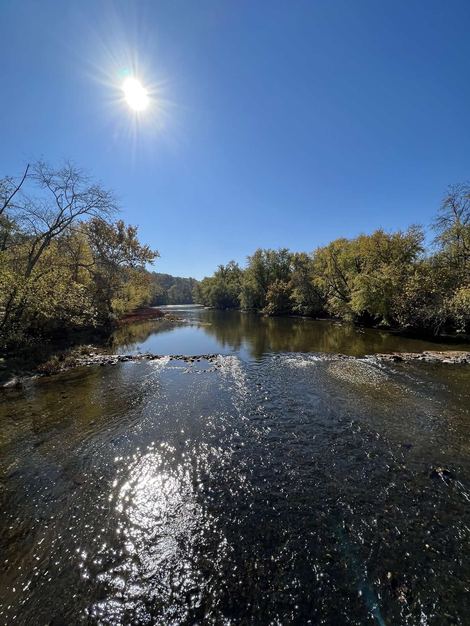 Bright sun reflects on a wide river surrounded by autumn trees. - Appalachian Trail: Boiling Springs to Route 850