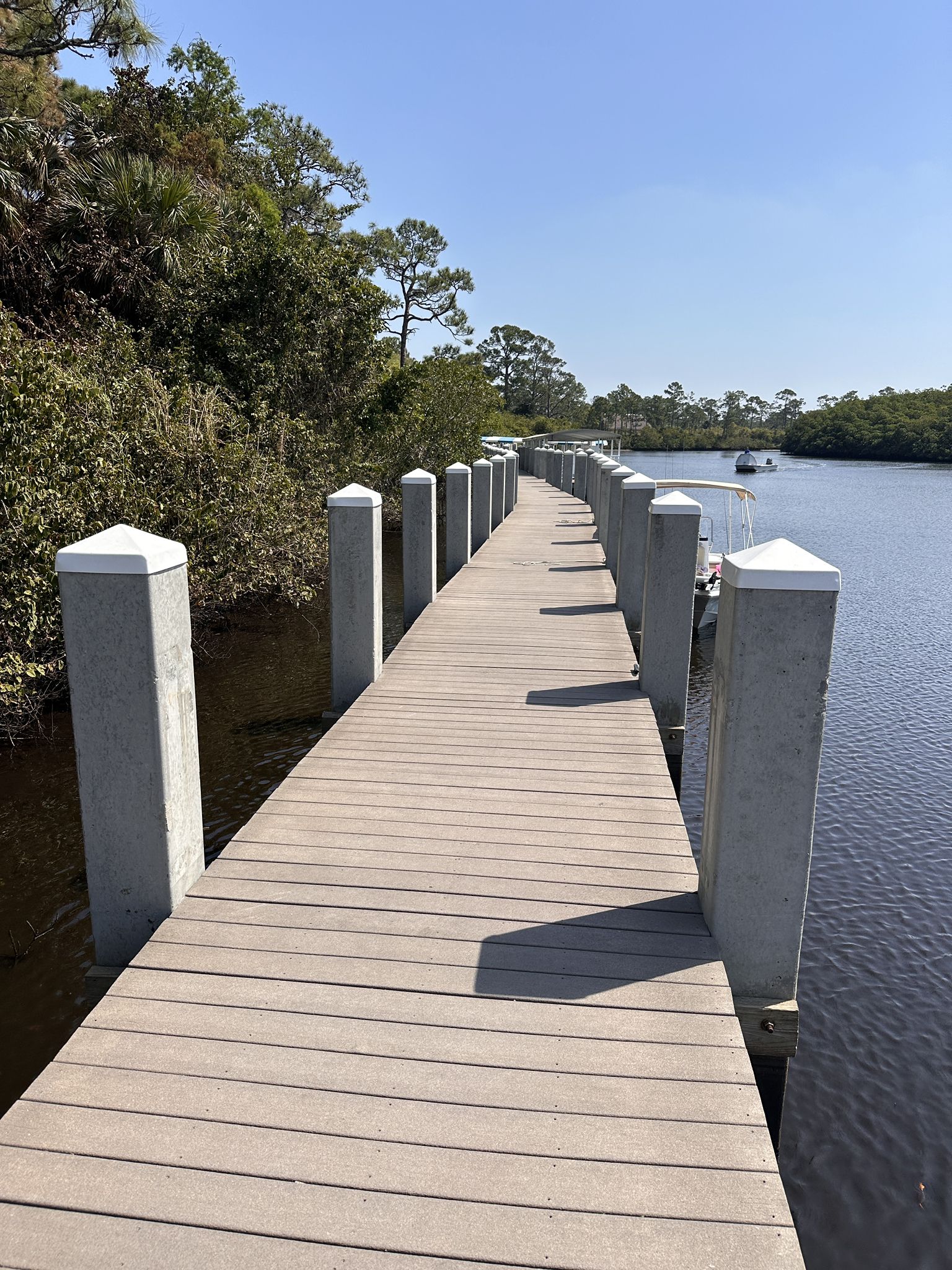 A long wooden dock with white posts stretches along a calm river. - Gator Alley Wildlife Viewing loop from Jonathan Dickinson State Park