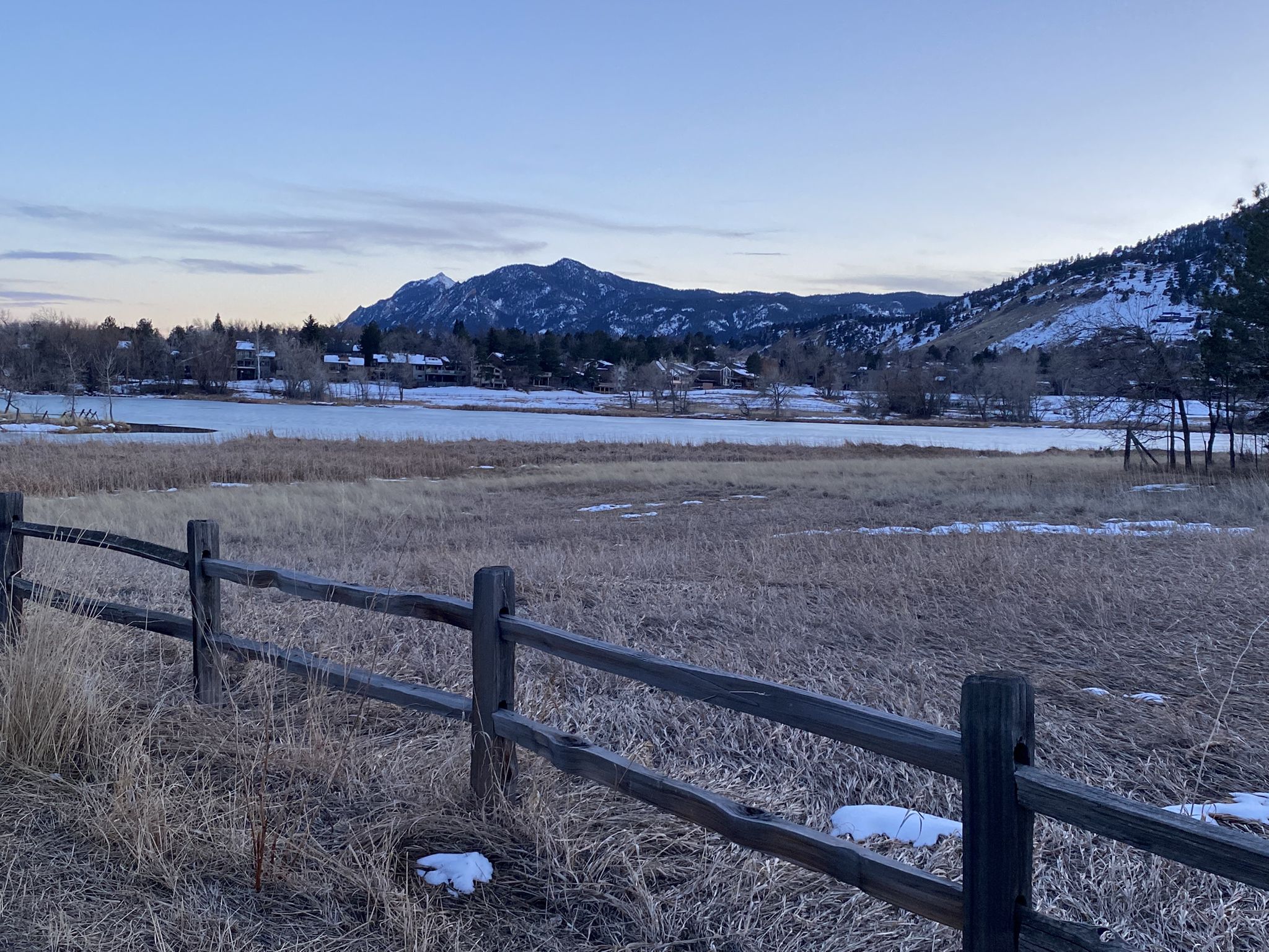 A wooden fence in front of a snowy field, frozen lake, and distant mountains. - Wonderland Lake – Lefthand Trail loop from 19th St & Joslin Ct