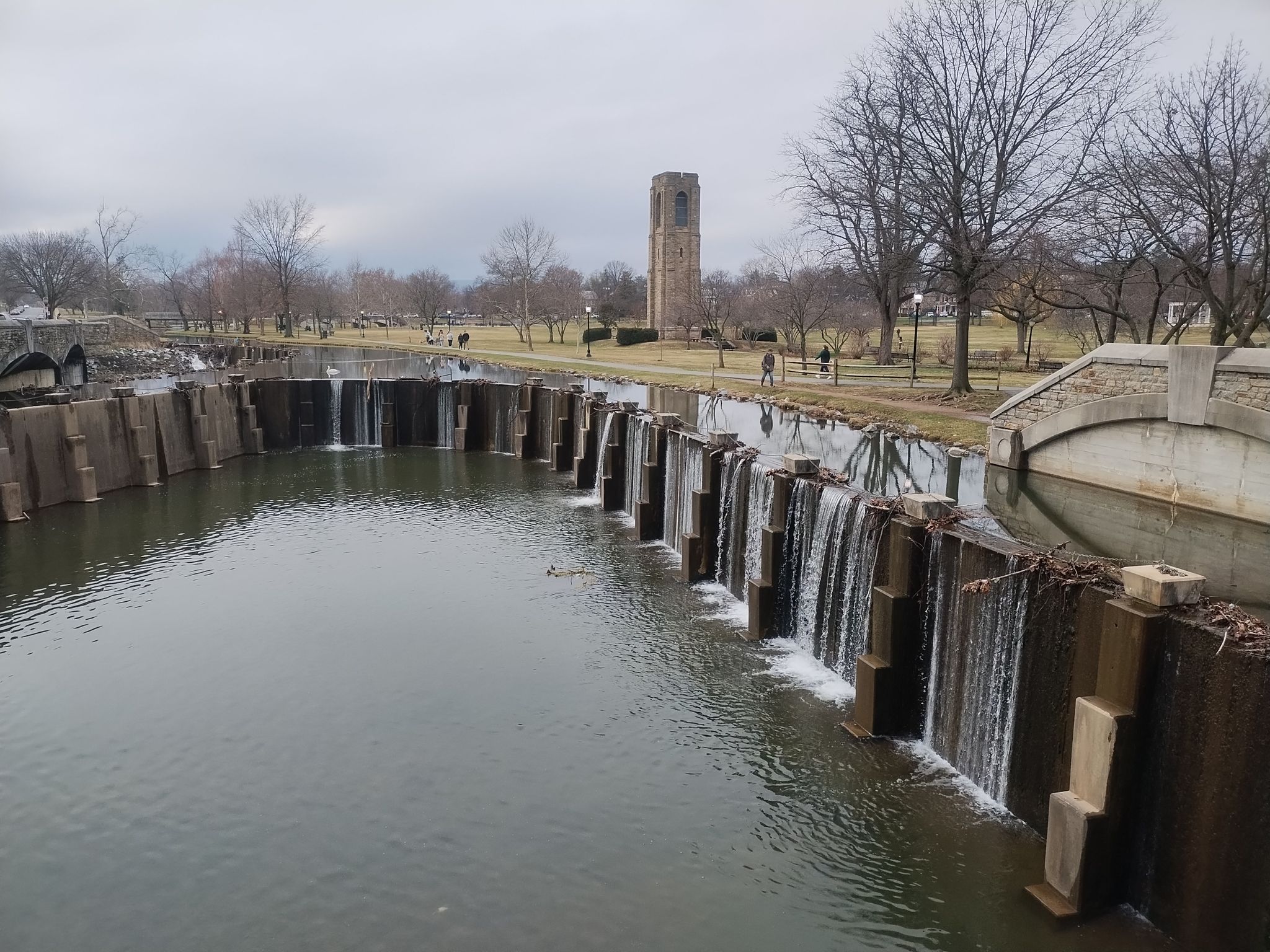Overcast view of cascading waterfalls, a stone tower, and bare trees in a park. - Rock Creek and Carroll Creek Trails