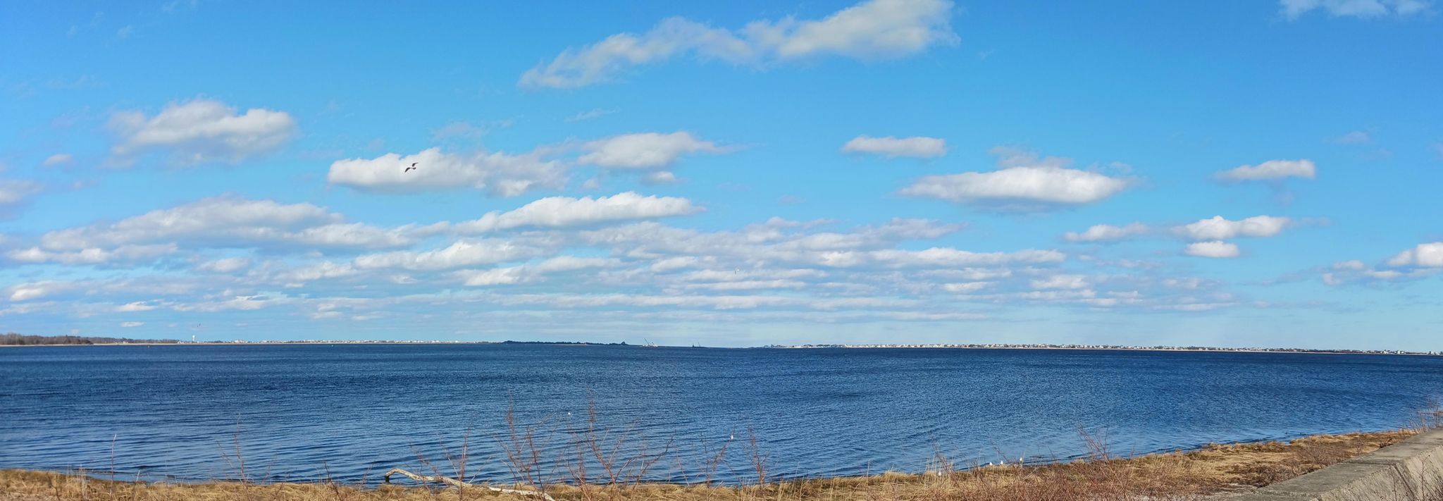 Panoramic view of a vast blue body of water under a partly cloudy sky. - Clipper City Rail Trail and Harborwalk Loop