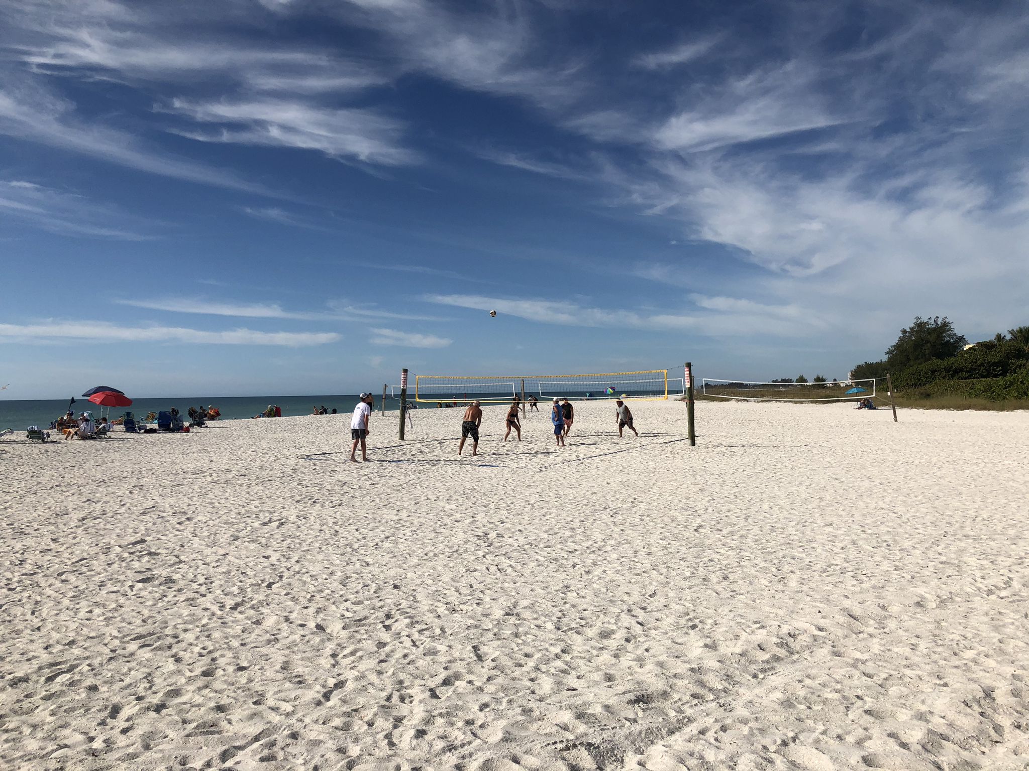 People playing beach volleyball on a sunny day with blue sky. - Anna Maria Island north loop from Manatee Beach Park