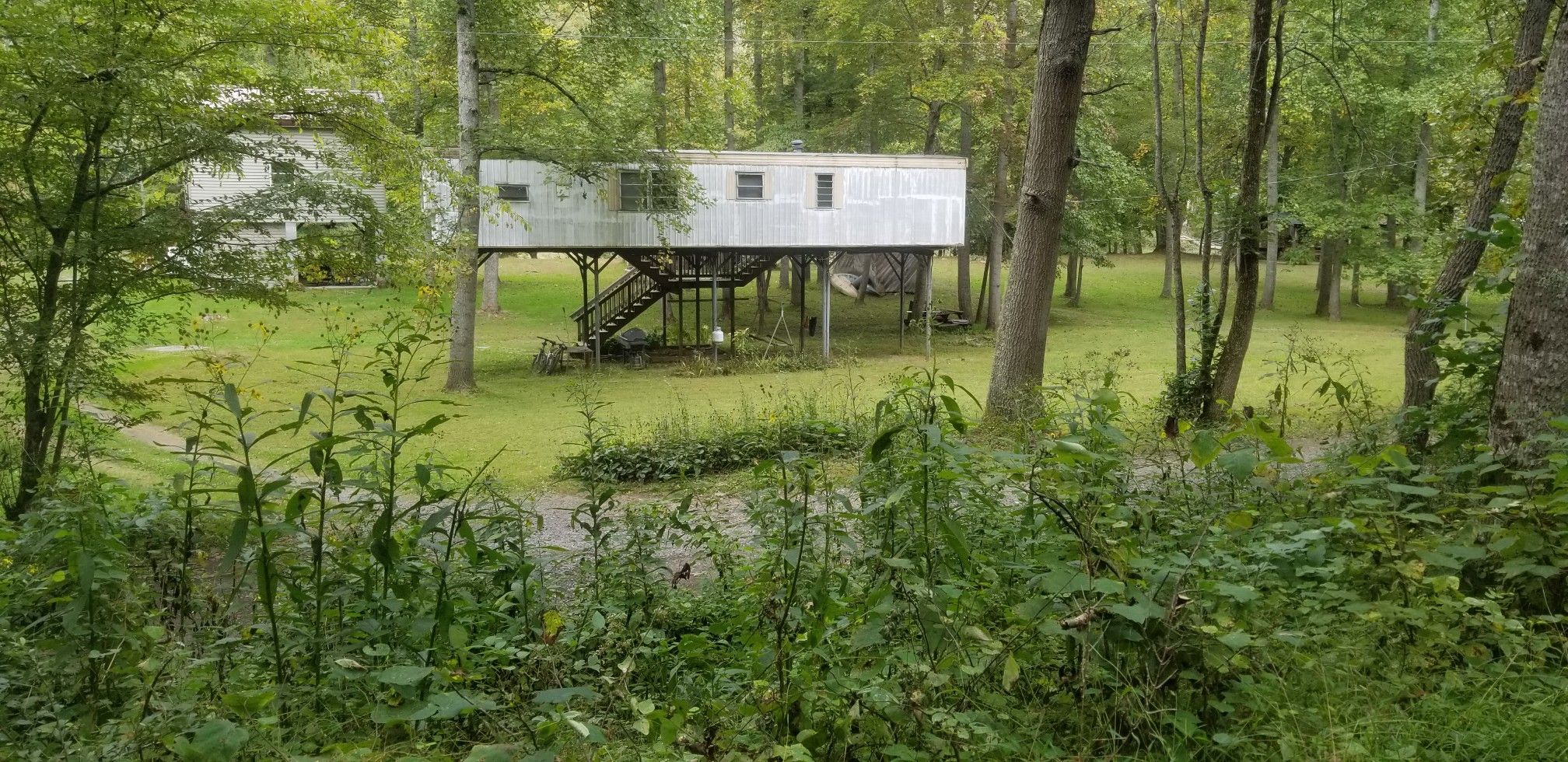 Elevated white building on stilts in a grassy clearing surrounded by trees. - Anthony Road – Nice view of Greenbrier River loop from Caldwell