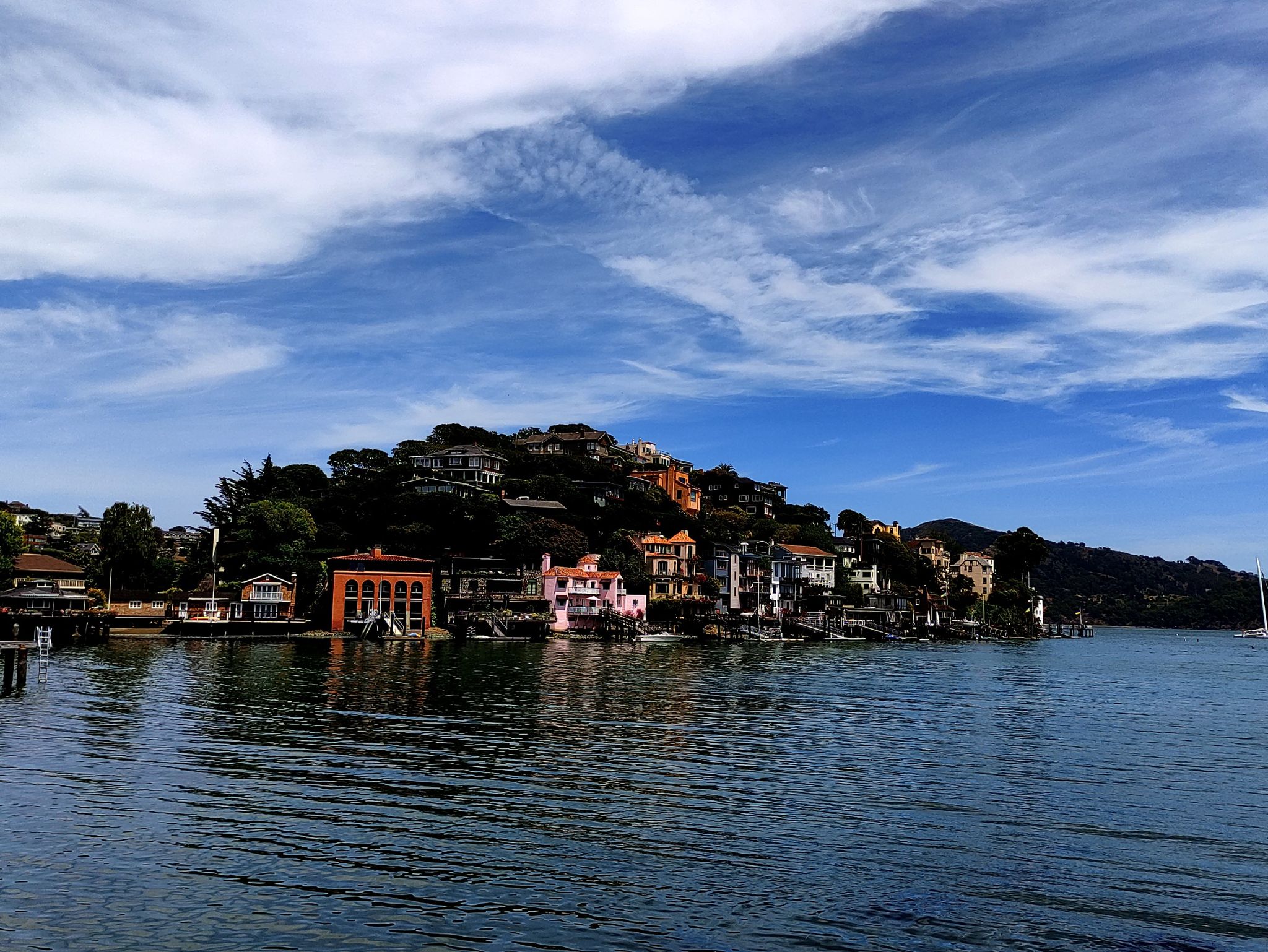 Colorful houses on a hillside overlooking calm water under a dynamic cloudy sky. - Running loop from Tiburon