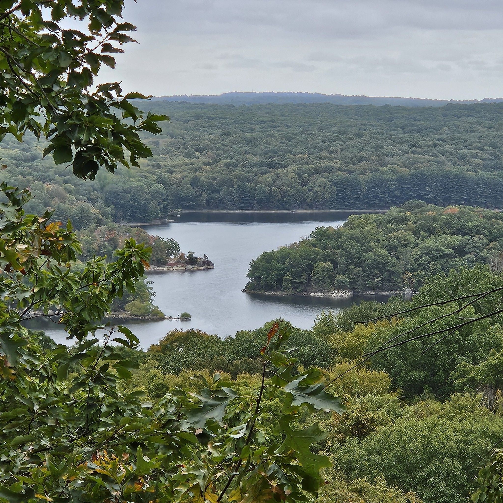 Overcast view of a winding lake surrounded by dense green forest. - Blue Blazes to The Ledge to Pillars Trail