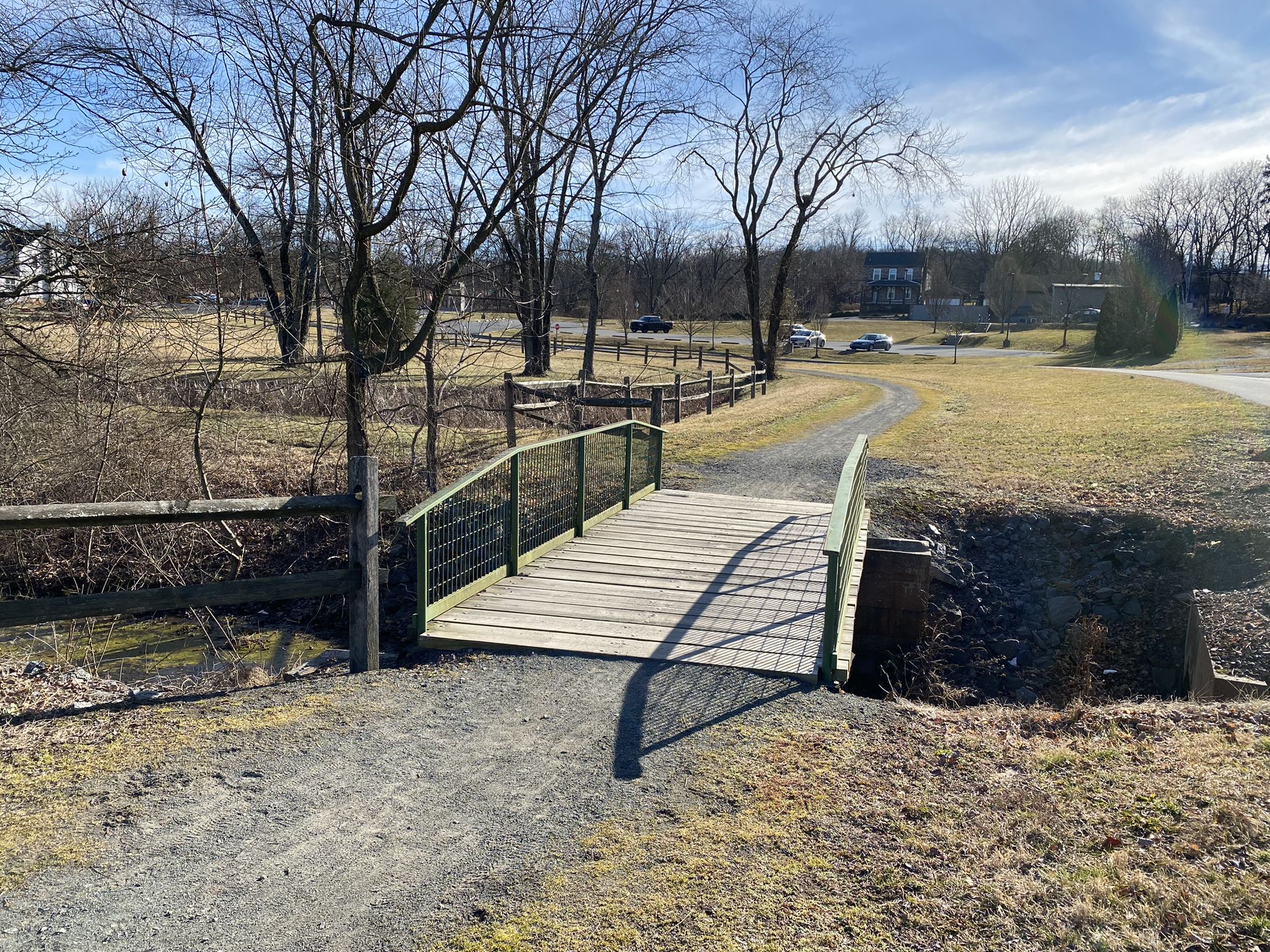 Wooden bridge with green railings over a small stream on a sunny day. - Schuylkill River Trail: Thun Section