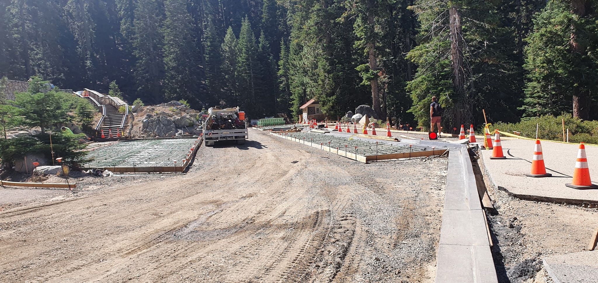 A construction site with a truck, orange cones, and forest in the background. - From Wawona Hotel to Glacier Point