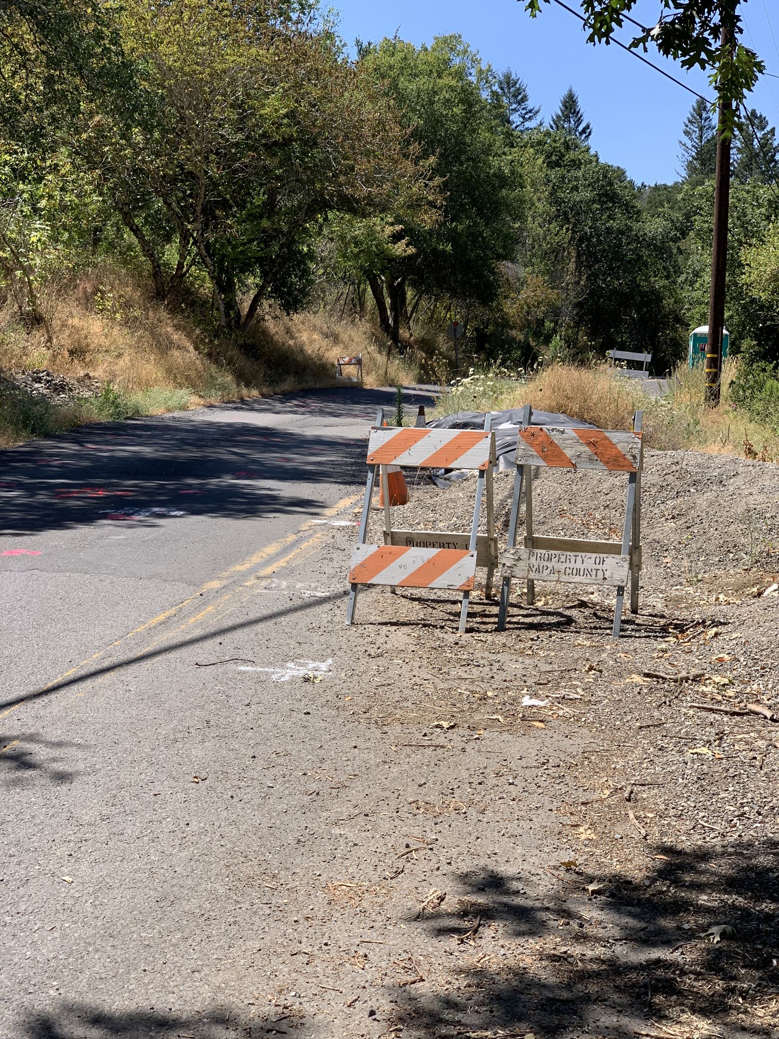 An empty road with orange and white construction barriers on a sunny day. - Enchanted Hills Loop