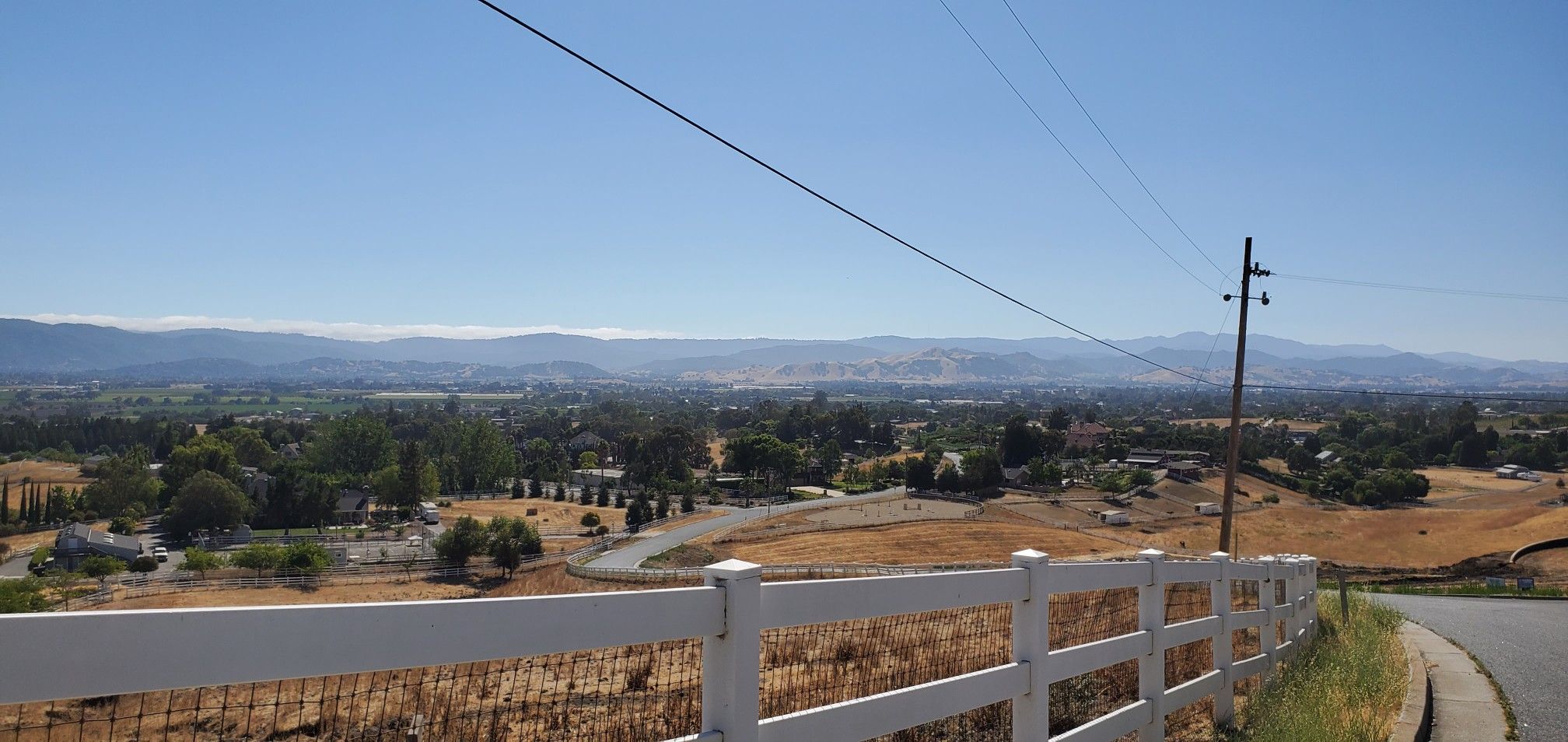 White fence overlooks a vast valley with distant mountains on a sunny day. - Site of 21-Mile House – 21 Mile Park loop from Morgan Hill