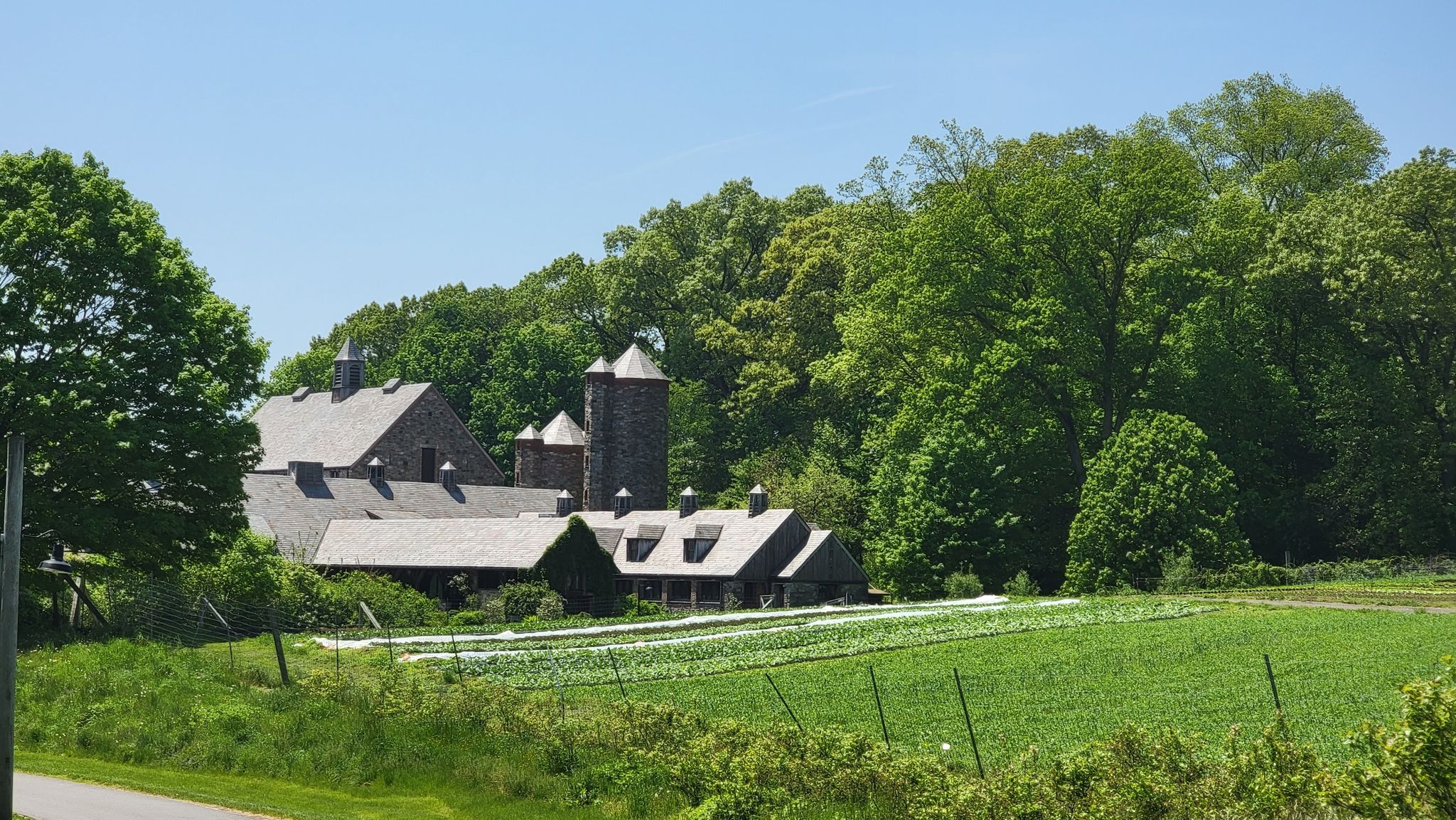 Large barn complex with silos next to a vibrant green field under a clear sky. - Buttermilk Hill to Reservoir Loop