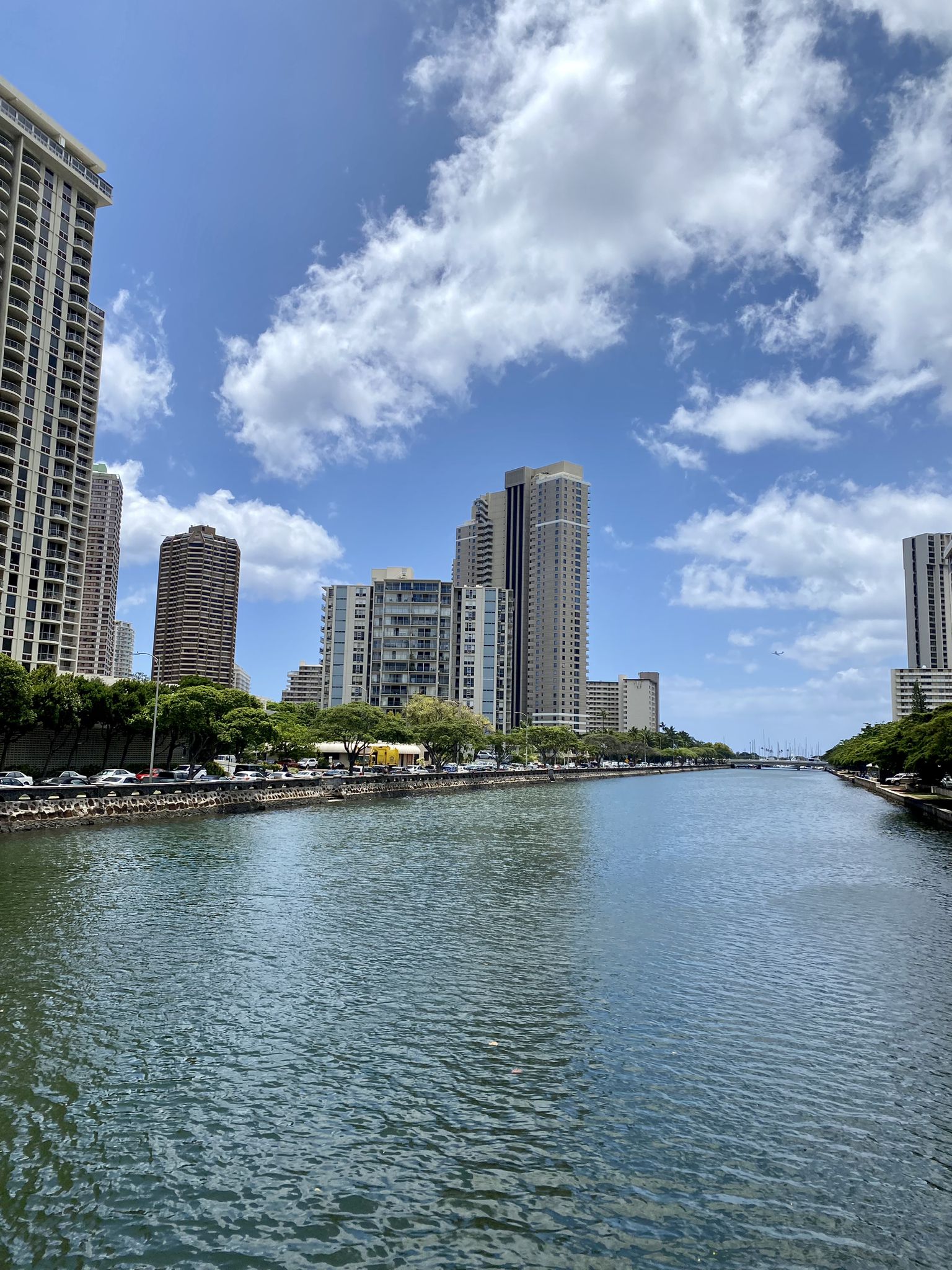 River flowing through a city with tall buildings under a blue sky. - Honolulu to Sand Island loop