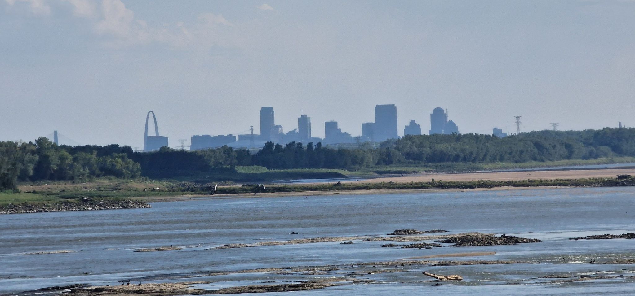 A distant city skyline with a prominent arch across a wide river. - Old Chain of Rocks Bridge – Old Chain of Rocks Bridge loop from Chouteau Island
