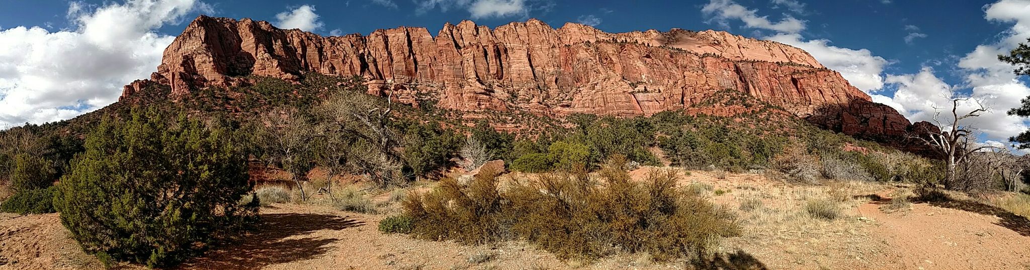 Panoramic view of a large red rock cliff under a partly cloudy sky. - Lee Pass to Wildcat Canyon
