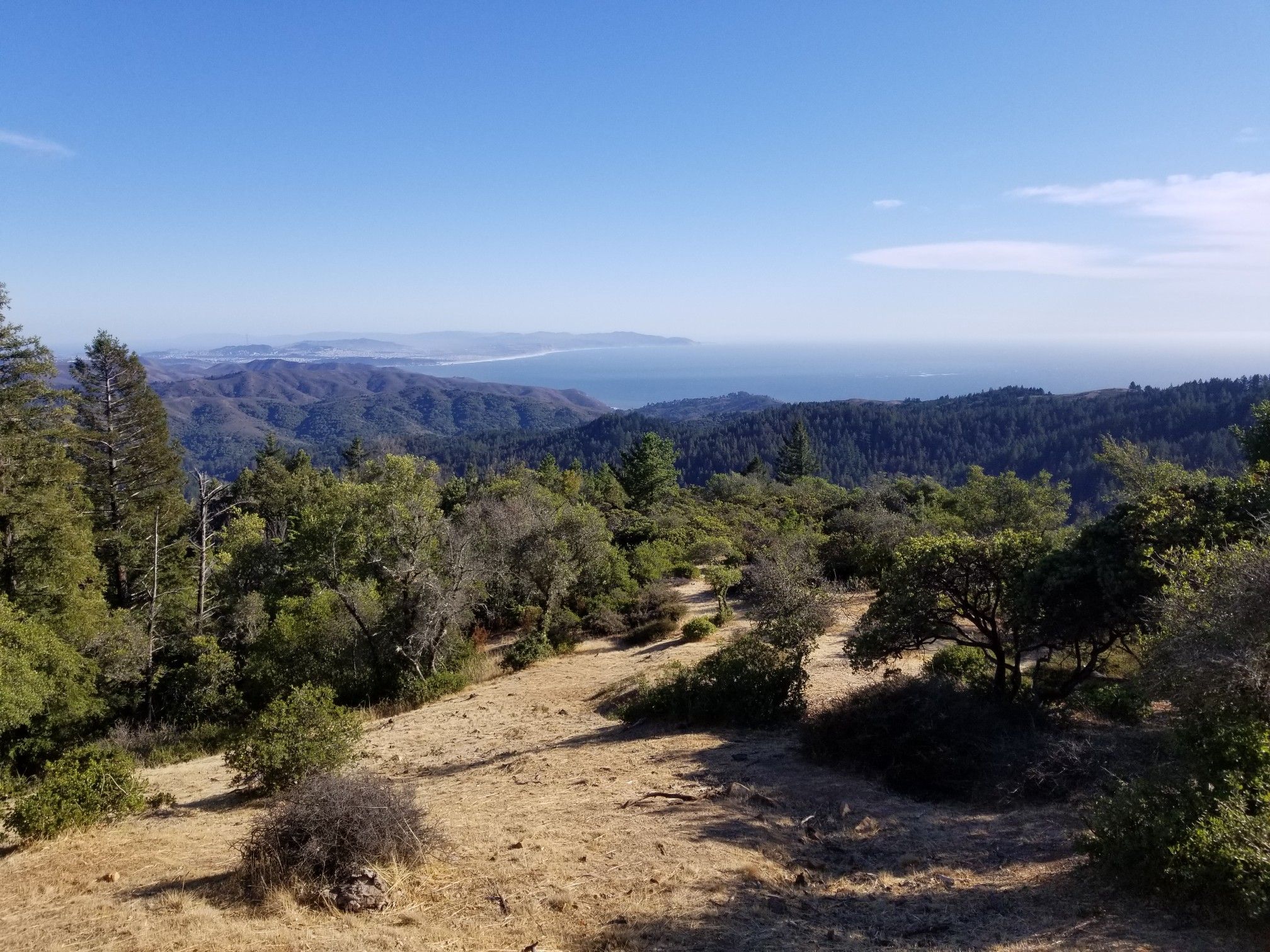 Panoramic view of rolling hills, distant ocean, and clear sky. - Hike to West Point Inn via Hogback and Nora Trail