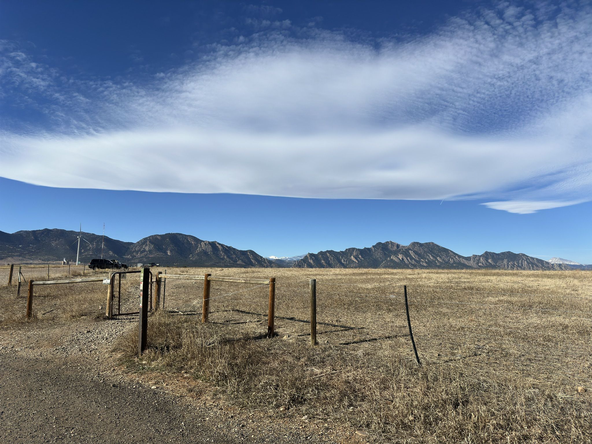 Dry field with a fence and distant mountains under a wide blue sky. - Marshall Mesa view – Meadowlark Trail loop from Boulder Open Space and Mountain Parks
