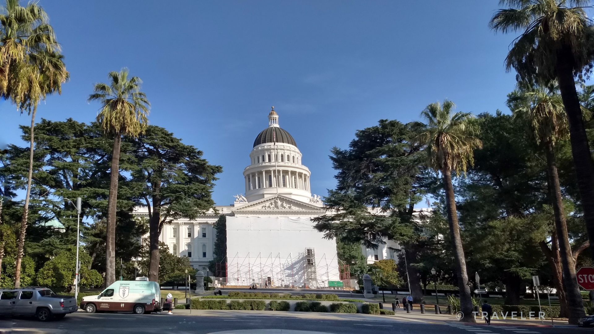 Grand white domed building, partially scaffolded, surrounded by palm trees under blue sky. - California State Capitol – Sacramento River Bike Trail loop from Cosumnes River College