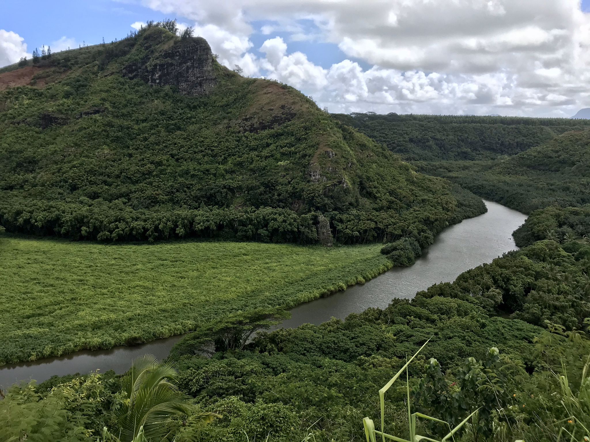 Panoramic view of a winding river through a lush green valley and mountains. - Kuamoʻo Road