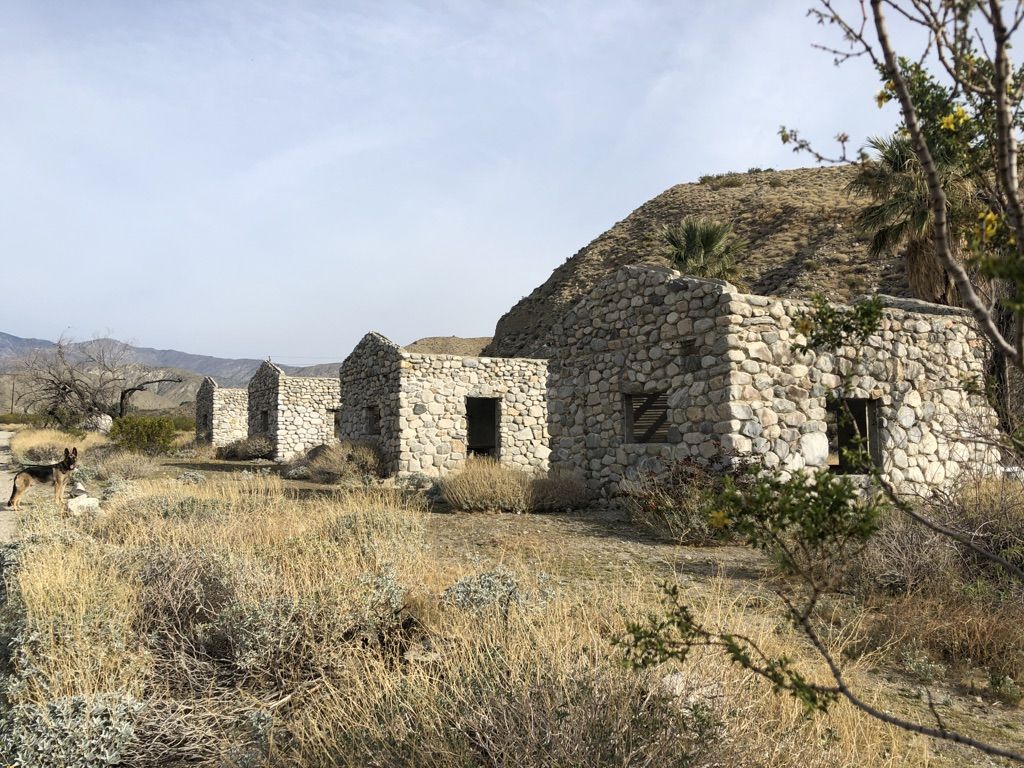 Row of stone ruins in a dry, grassy landscape under a bright sky. - Mission Creek Shelter – San Bernardino National Forest