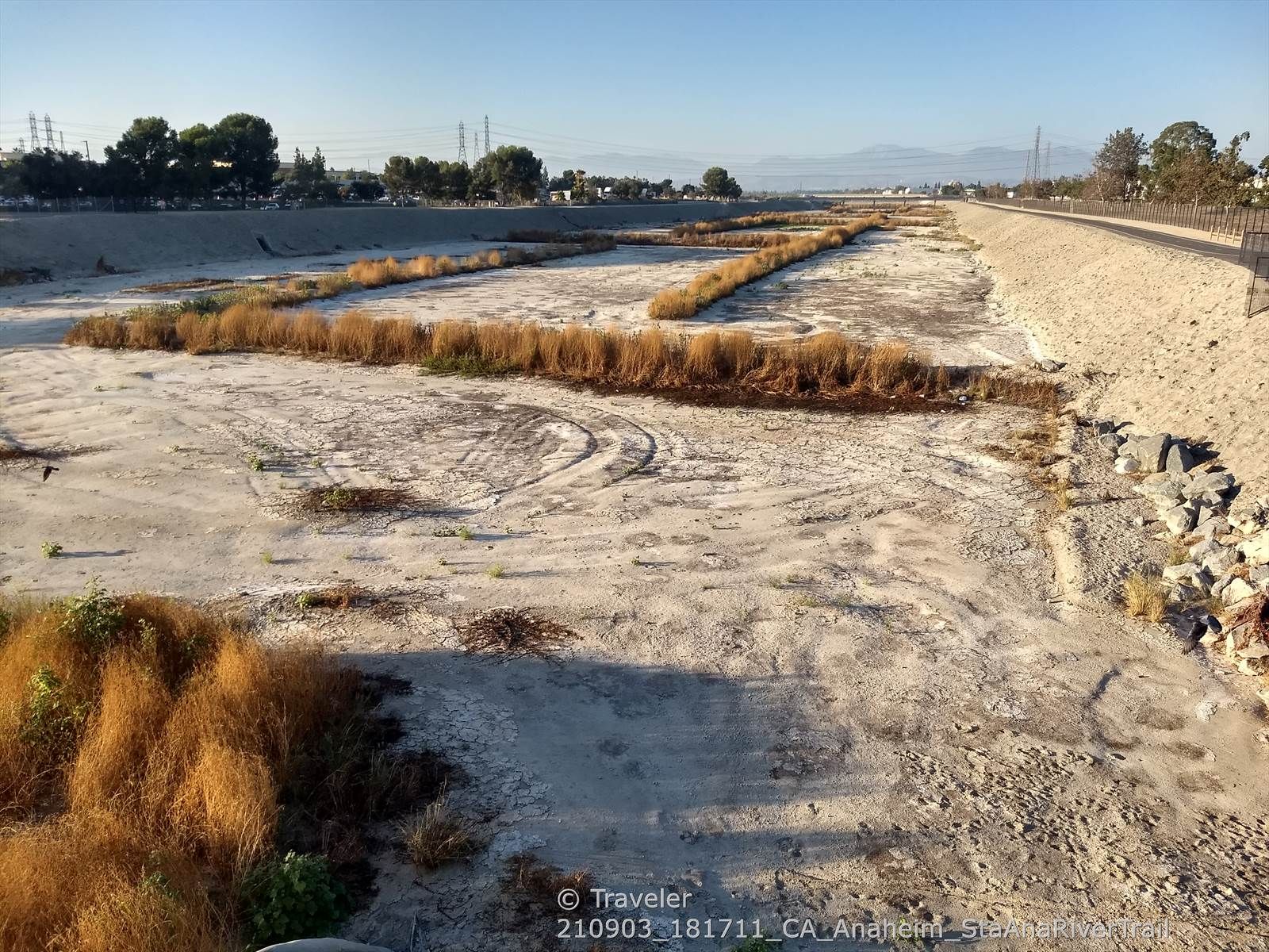 Wide dry riverbed with rows of brown vegetation and tire tracks. - Santa Ana River Trail – Santa Ana River Trail loop from Estancia High School
