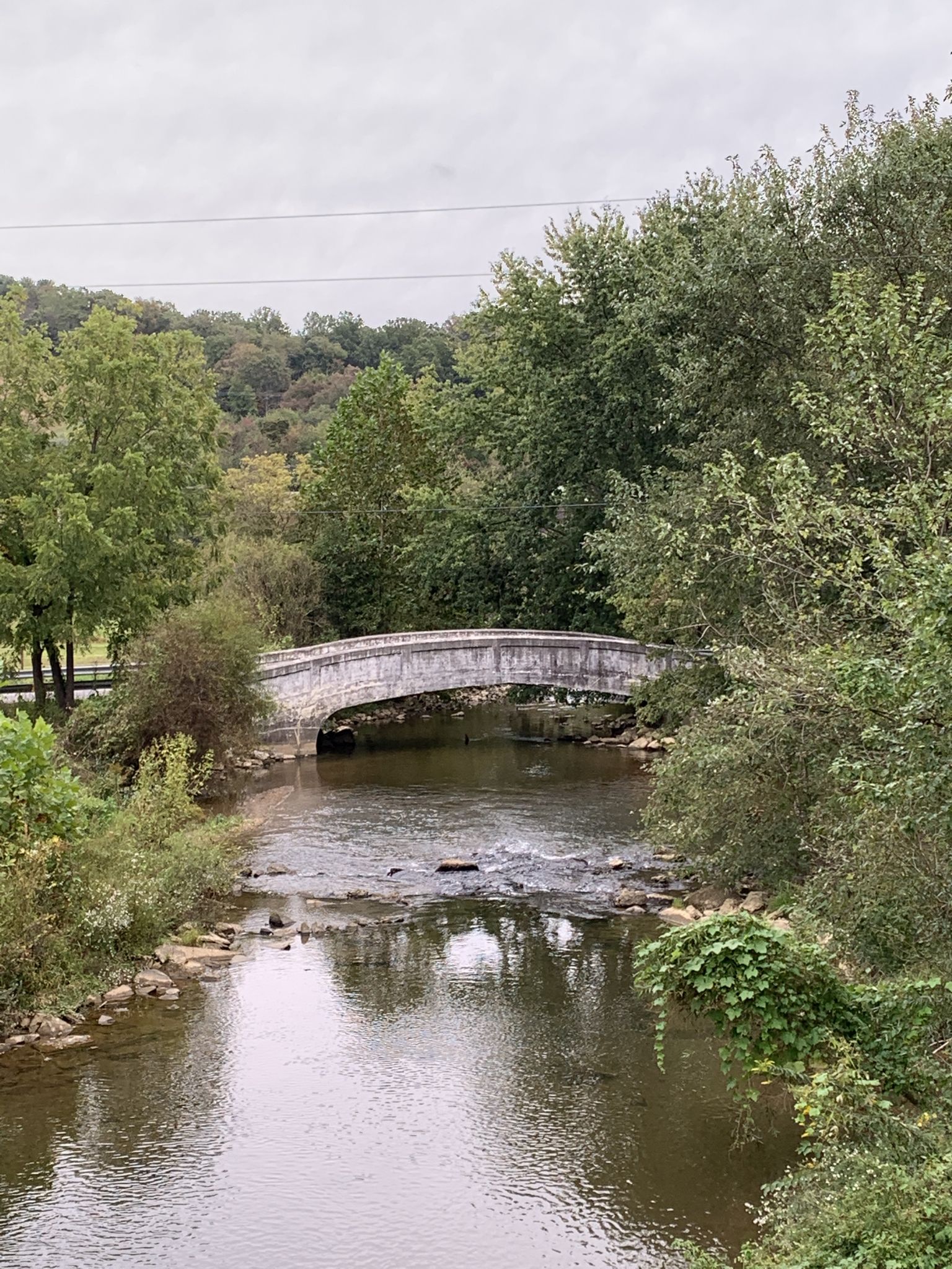 A stone arch bridge over a river, surrounded by green trees. - Bike loop from Glen Rock